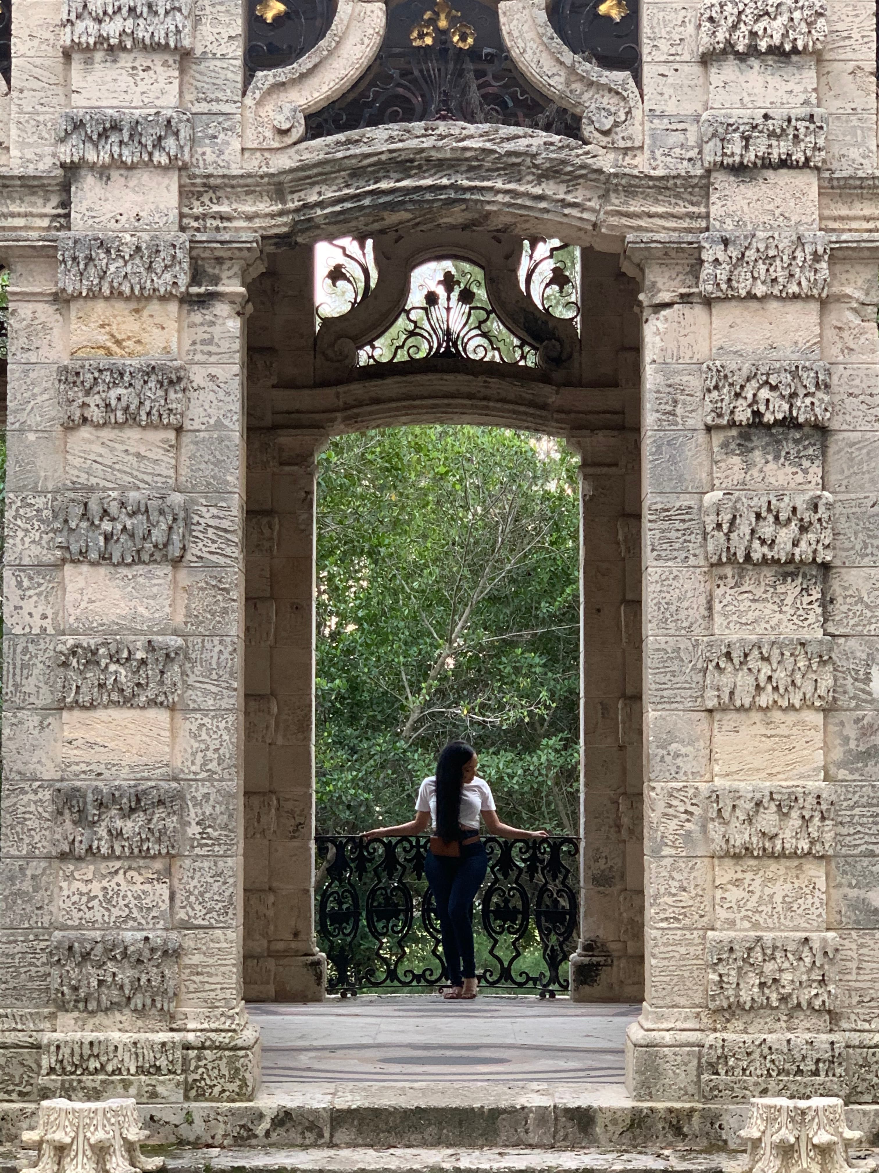 Advisor standing on a small balcony in an old stone building looking towards trees in the distance