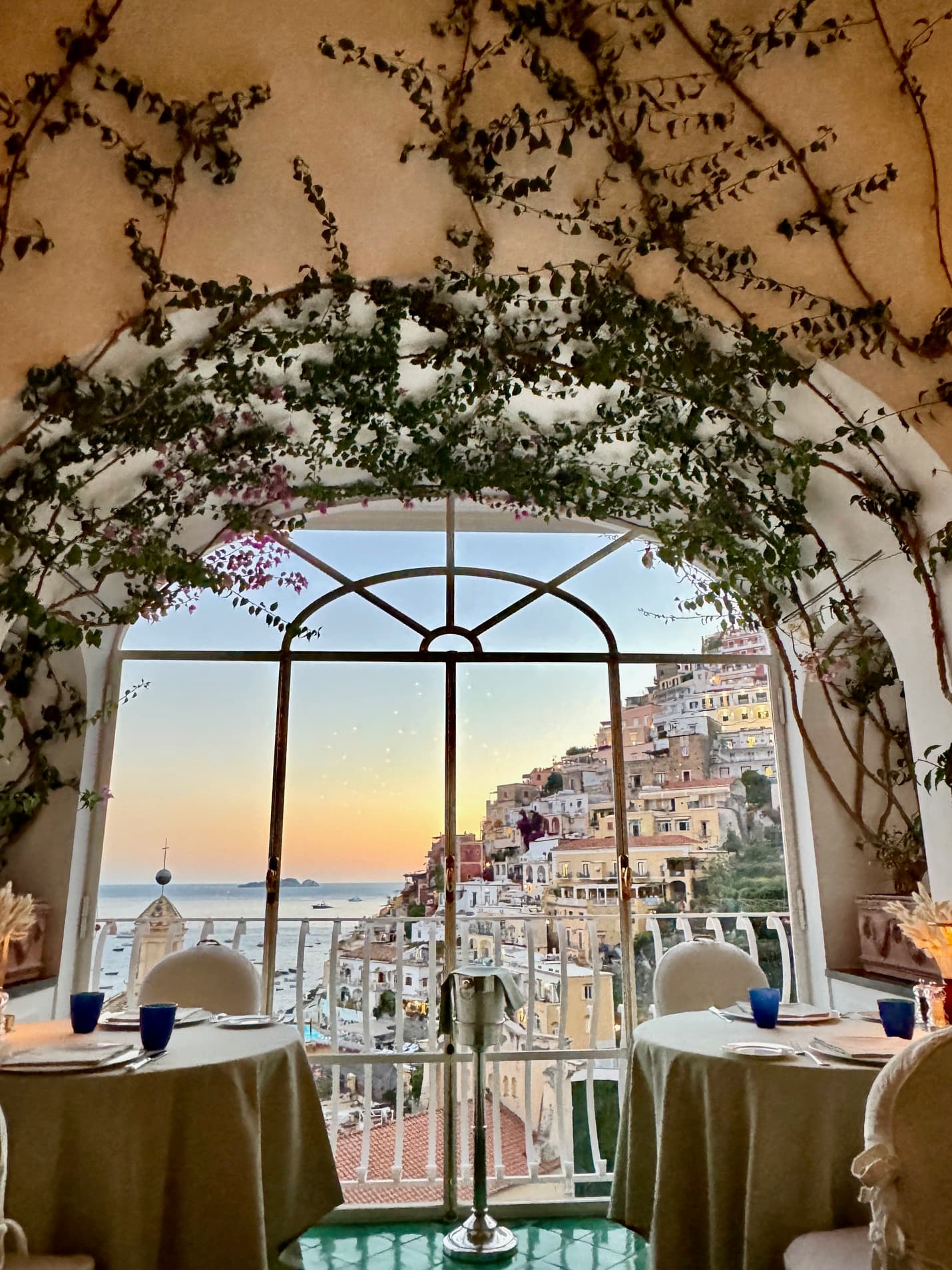 Beautiful view of a restaurant with a large glass window looking out over a coastal hillside town at sunset