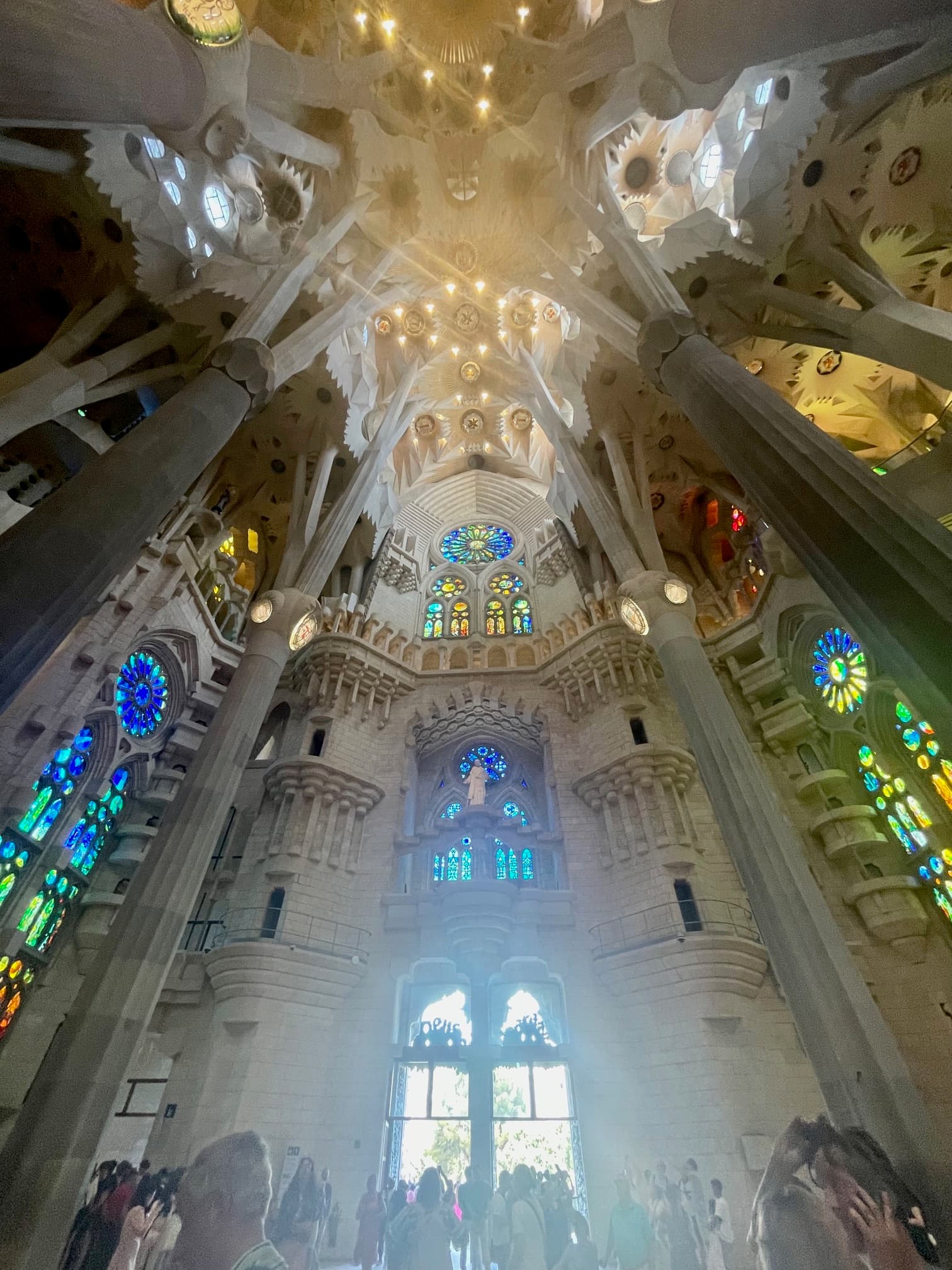 Interior view of a massive cathedral with sunlight streaming through stained glass windows