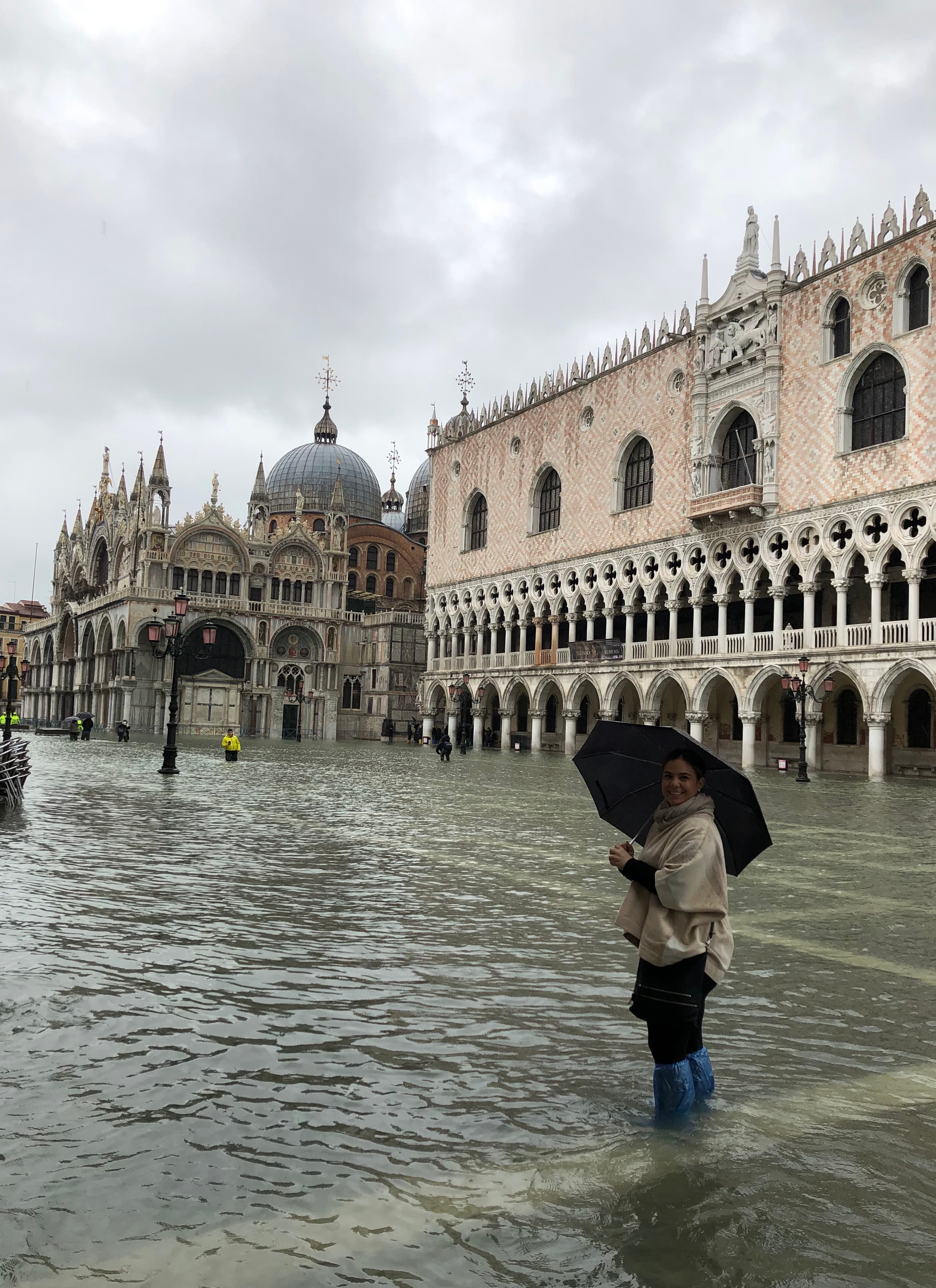 Advisor holding a large black umbrella in an old city plaza lined with beautiful buildings