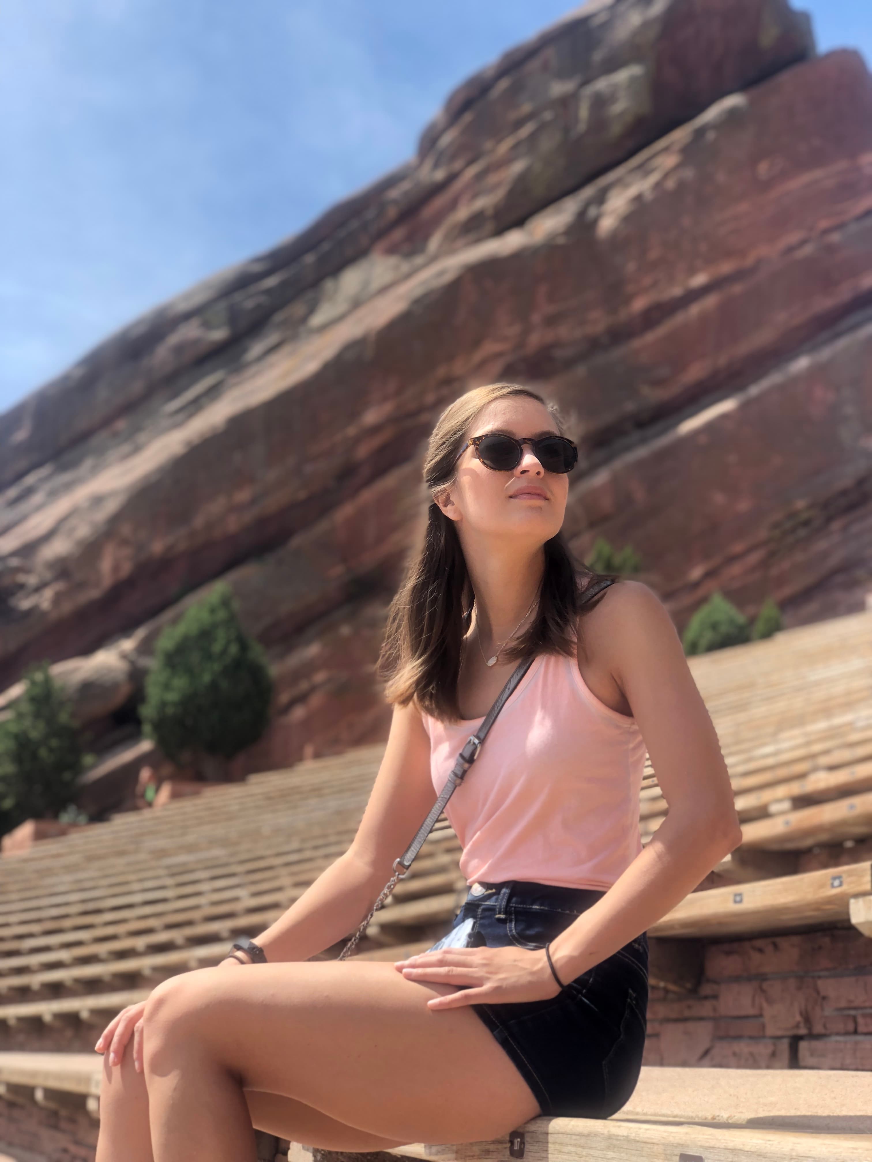 Advisor sitting on the steps at Red Rocks Amphitheatre on a clear day in Colorado