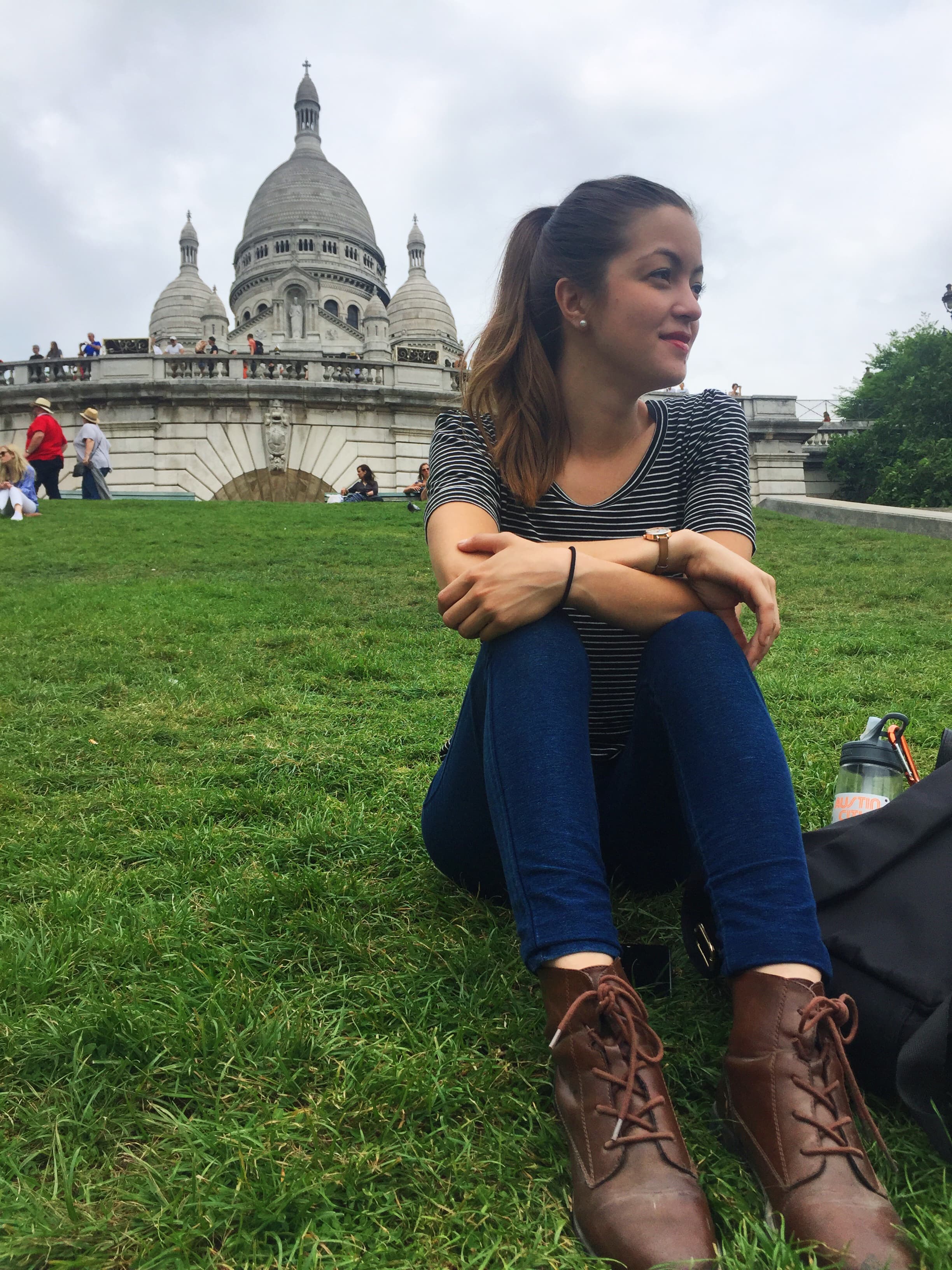 Advisor sitting on a grassy hillside with a white-domed cathedral on the hilltop behind her