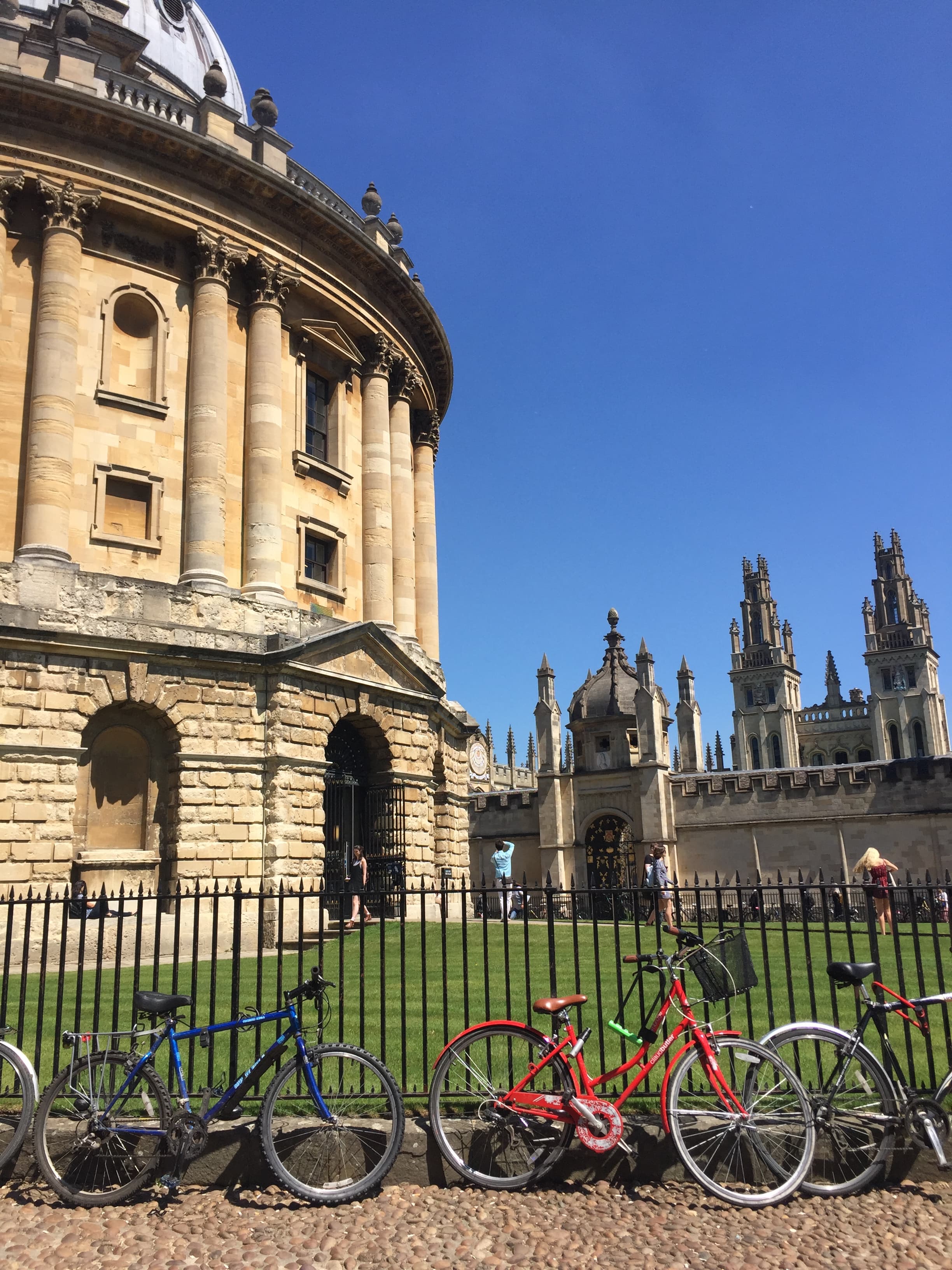 Bicycles parked against a gate with a large cathedral visible in the distance under clear skies