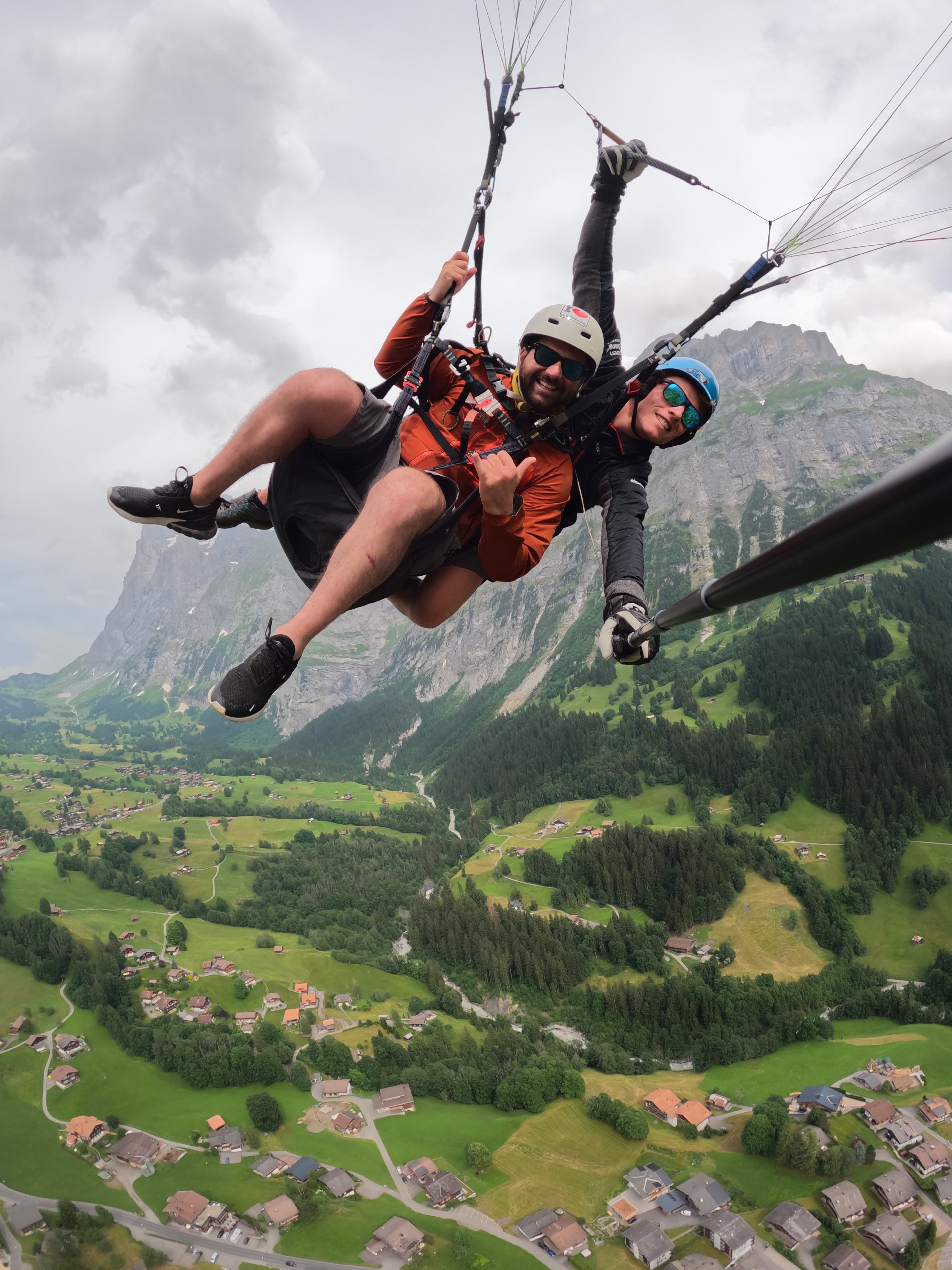 Advisor and partner paragliding high above a lush valley