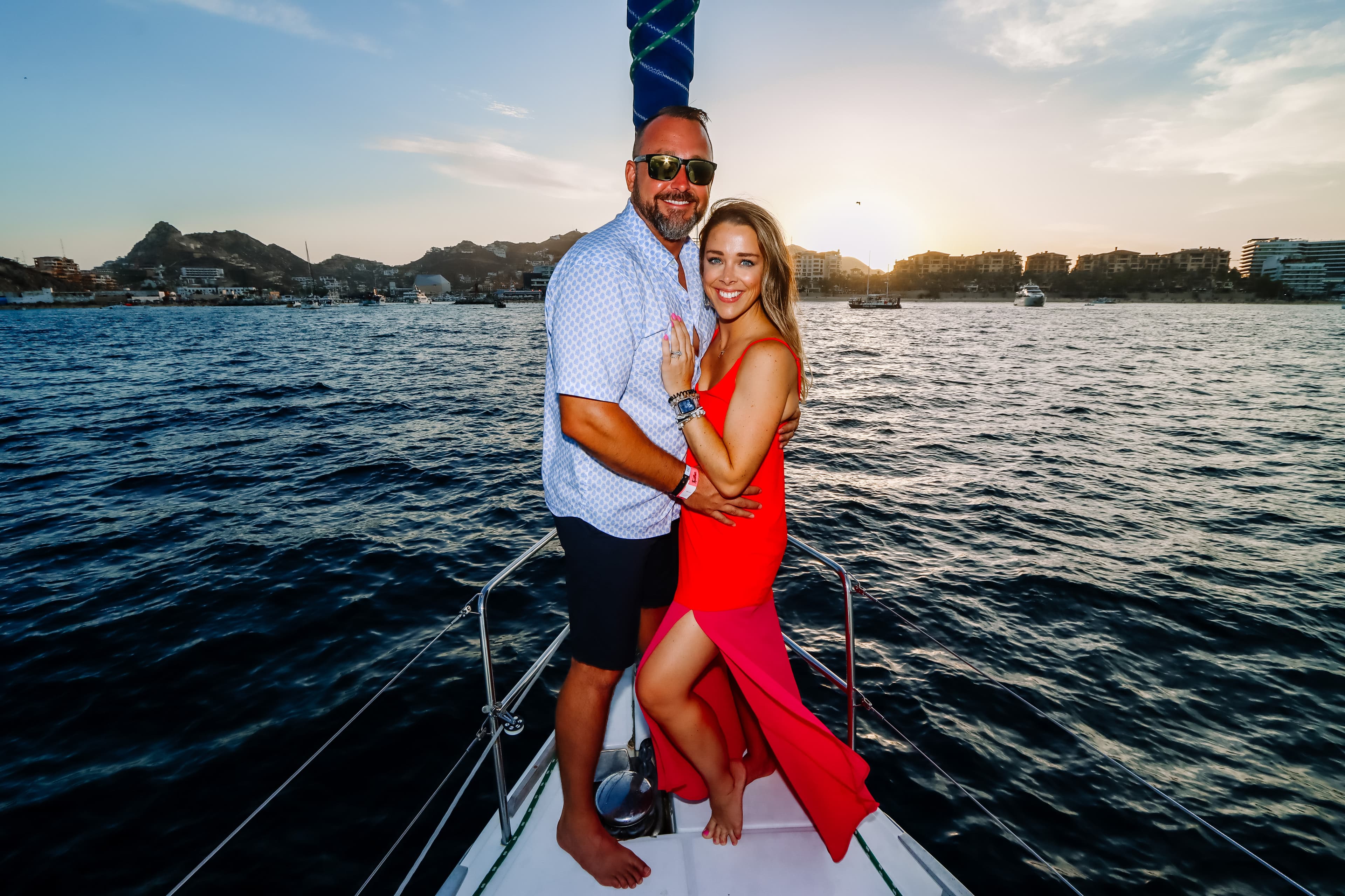 Advisor and partner posing together on a boat at sunset