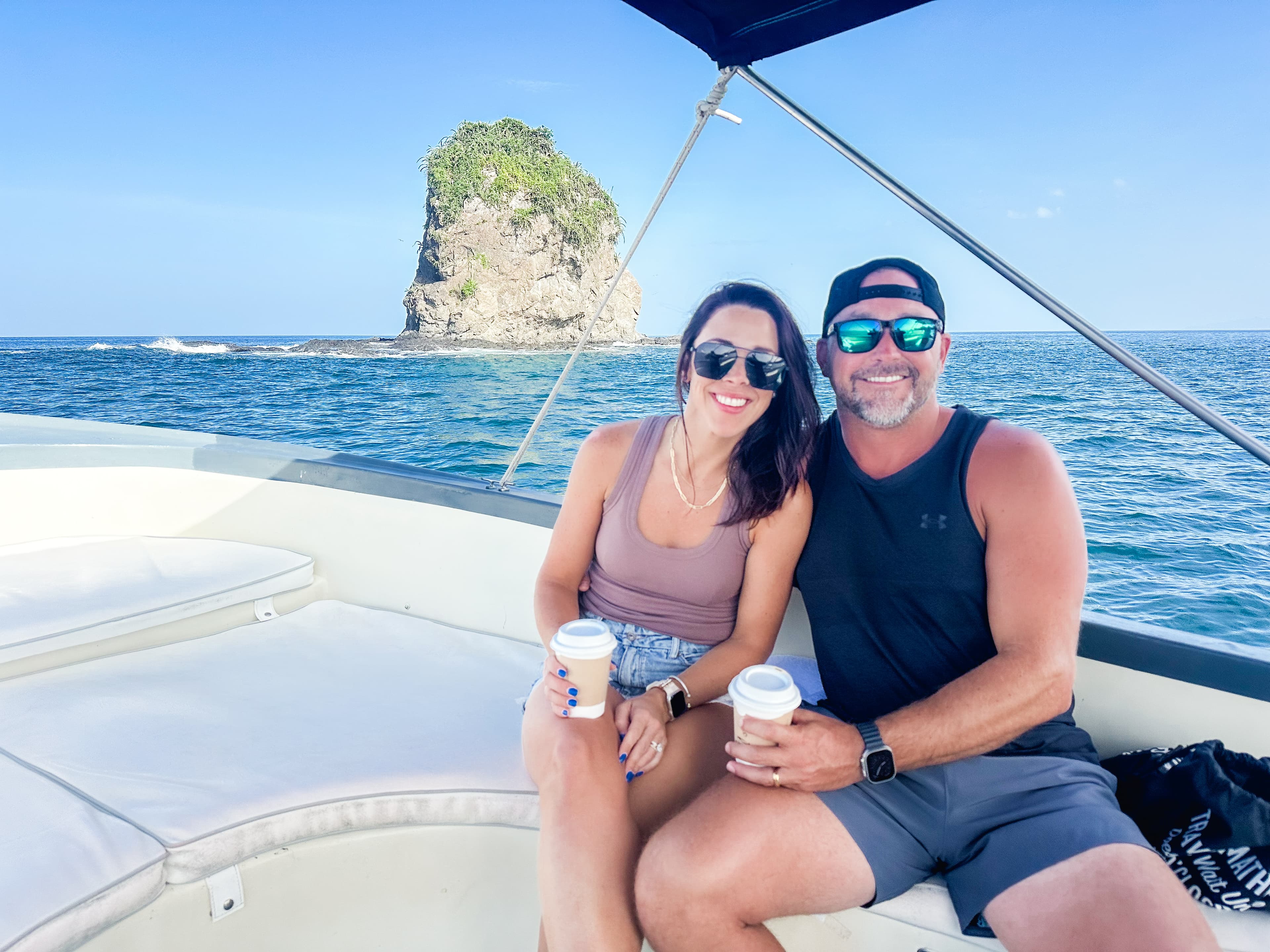 Advisor and partner smiling while holding cups on a boat on a clear day