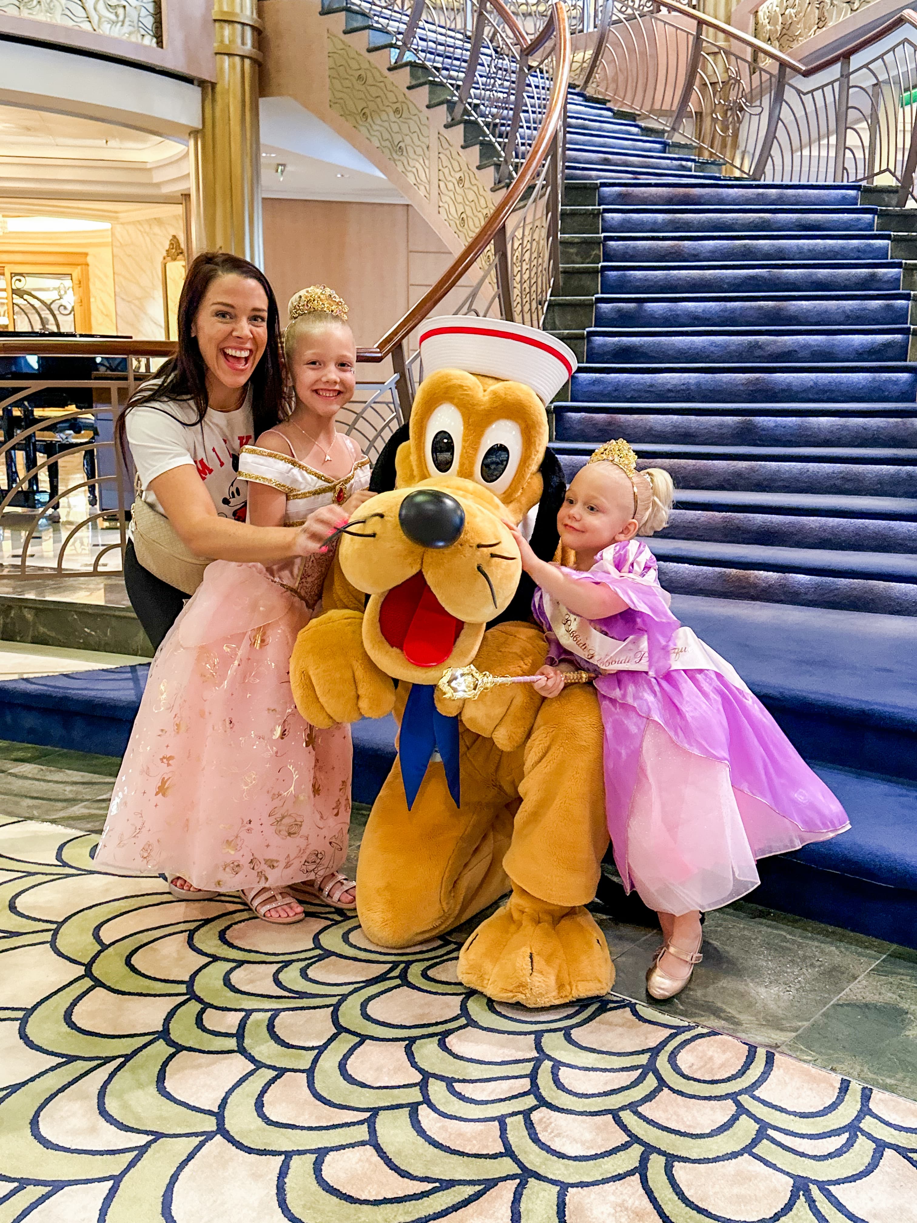 Advisor and her daughters smiling and posing together with Goofy on a cruise ship