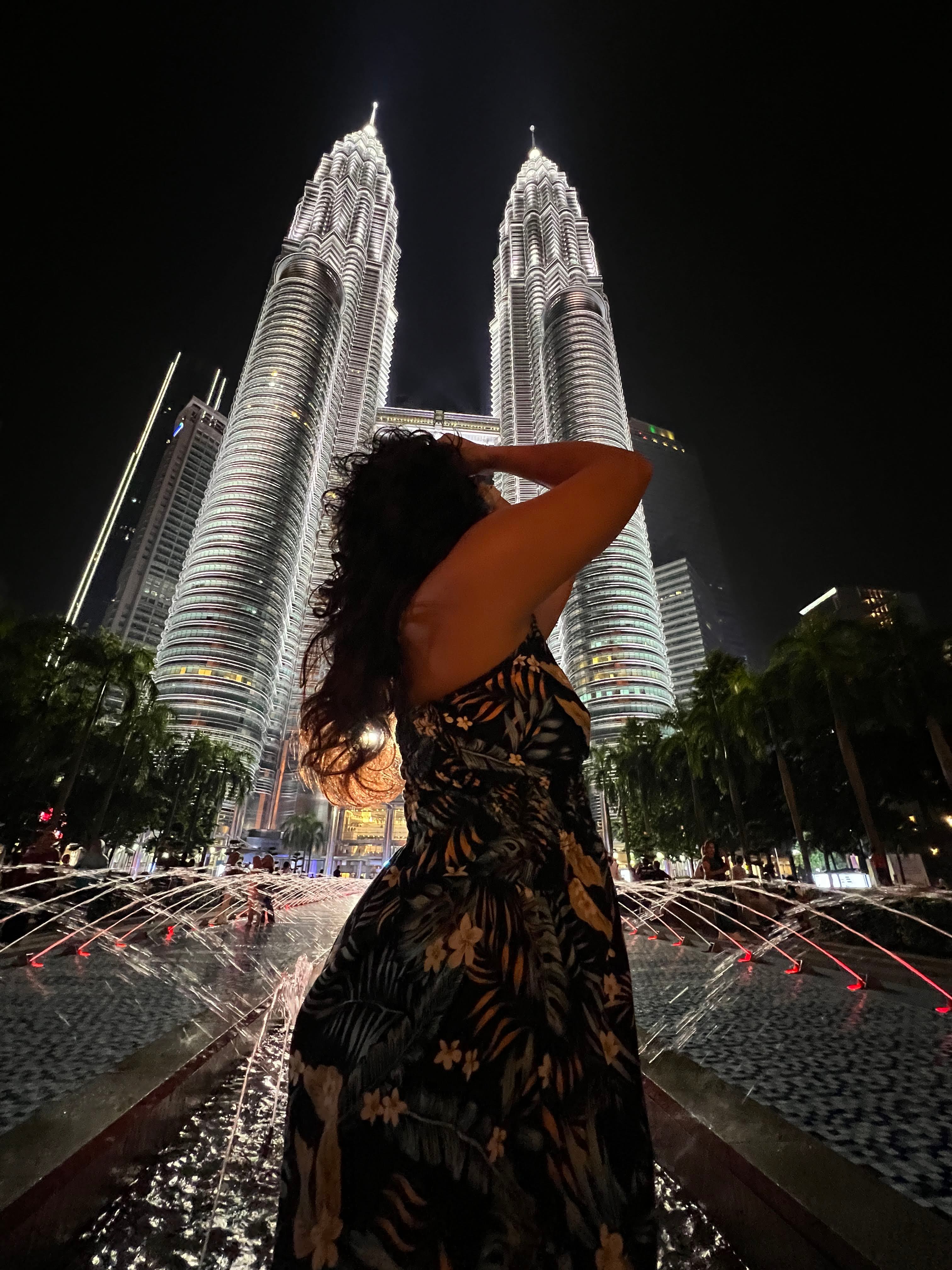 Advisor looking away from the camera and posing with a skyscraper lit up behind her at night