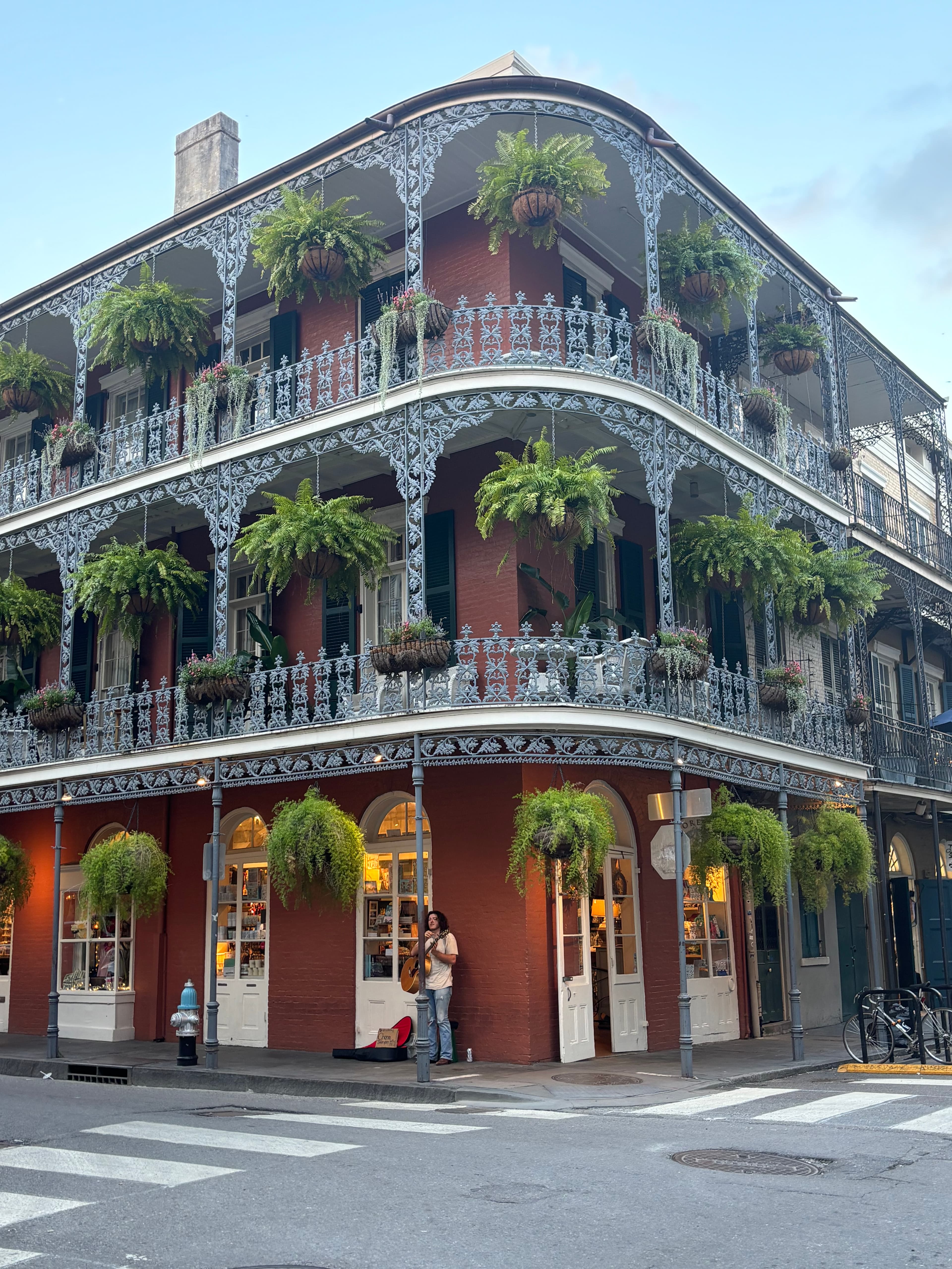View of a corner building with two wrap-around terraces fitted with hanging potted plants
