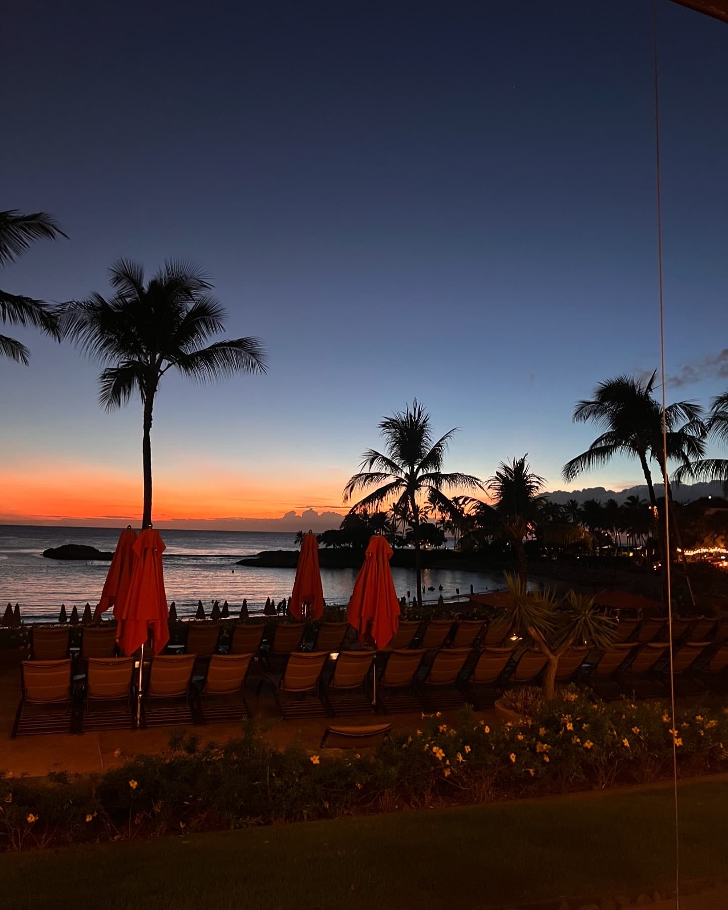 The last light of an orange sunset over the sea as seen from a resort beach
