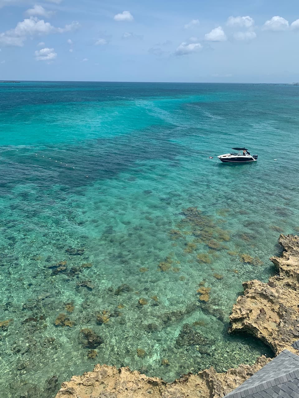 View of crystal clear ocean water with a small boat anchored off shore