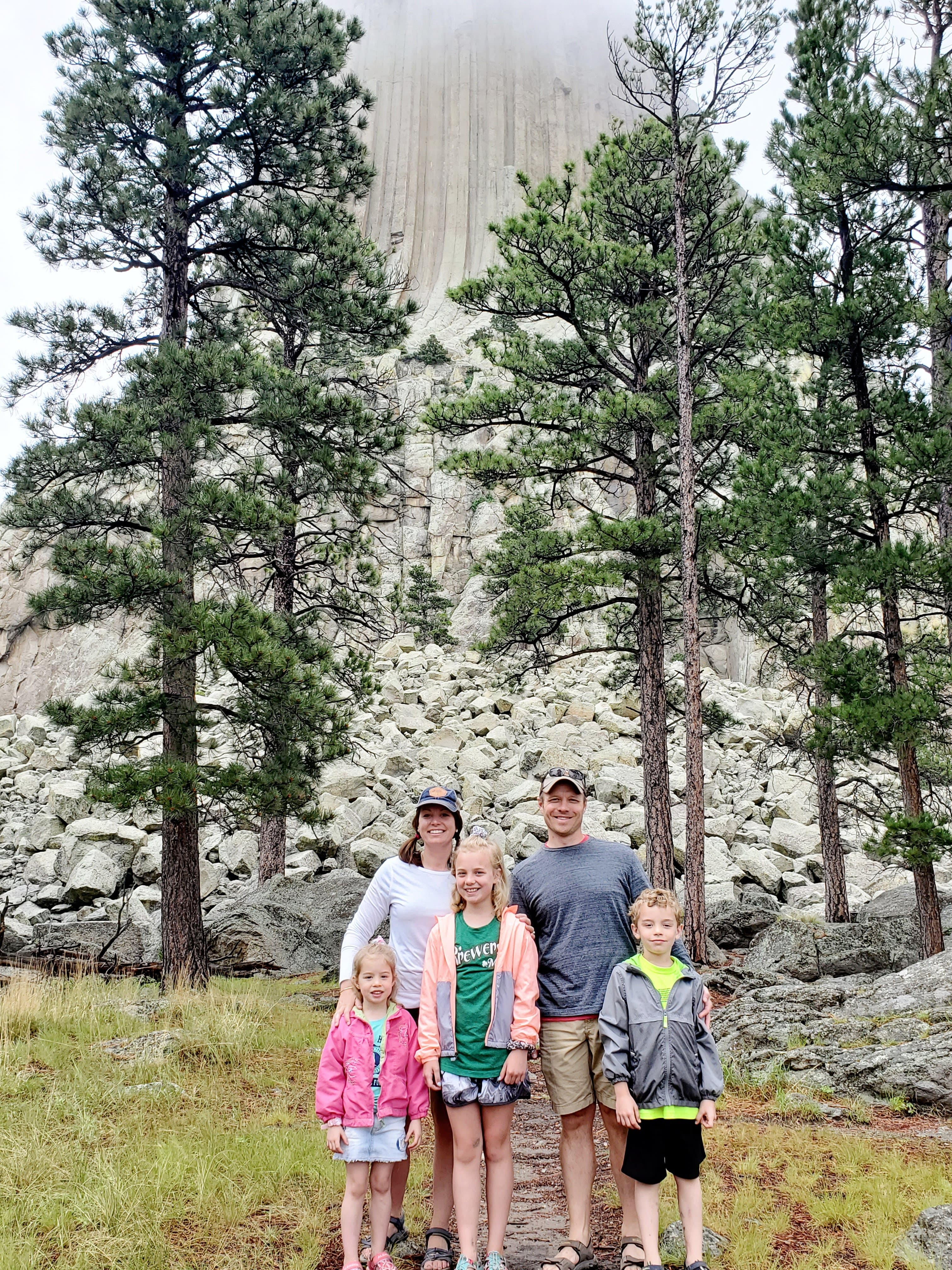 Advisor and family posing together on a home with trees and mountains in the mist behind them