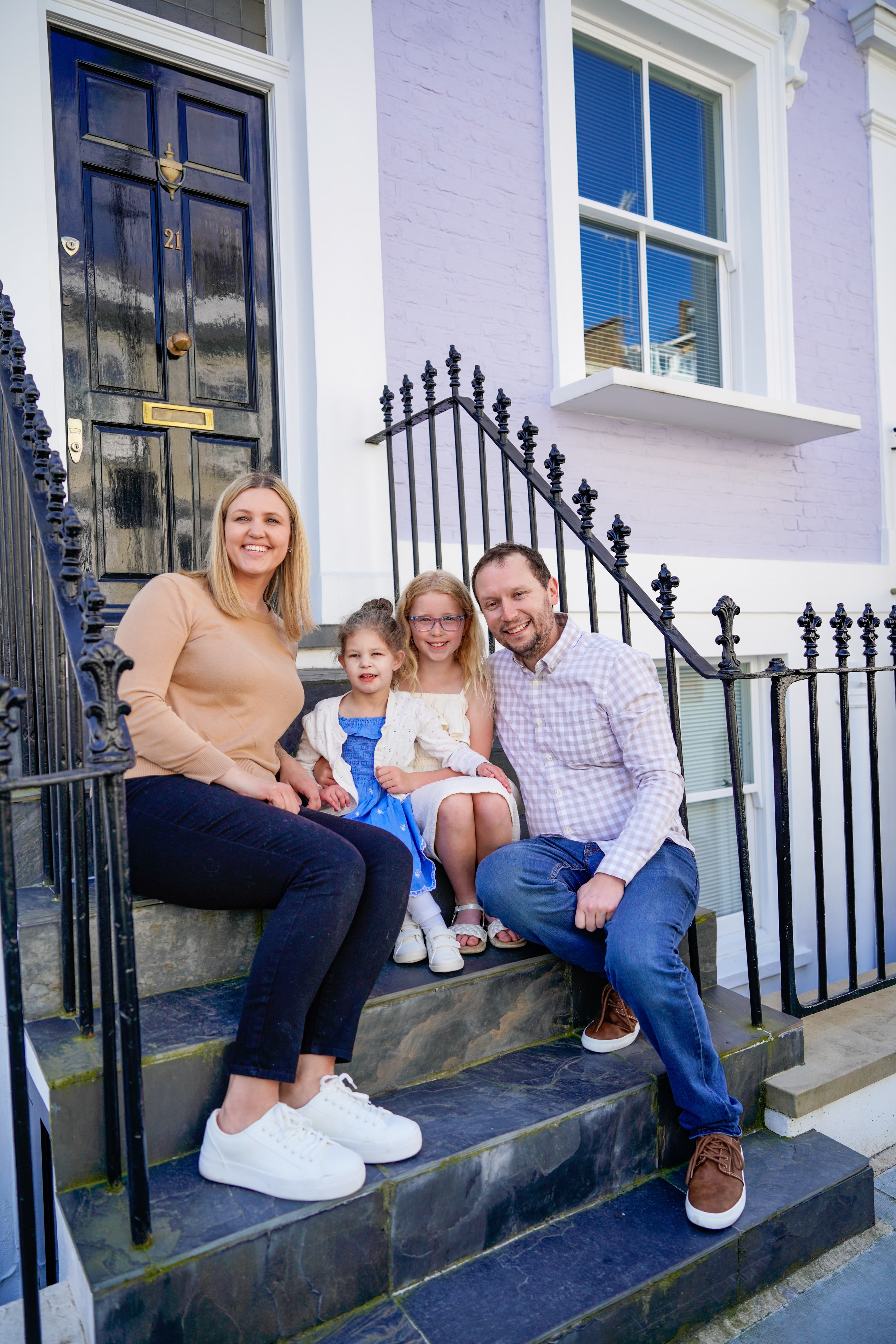 Advisor and family sitting on the front steps of a townhouse on a sunny day