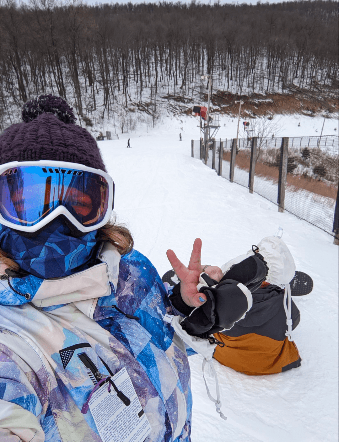 Advisor in ski goggles posing with a peace sign on a snowy mountain path