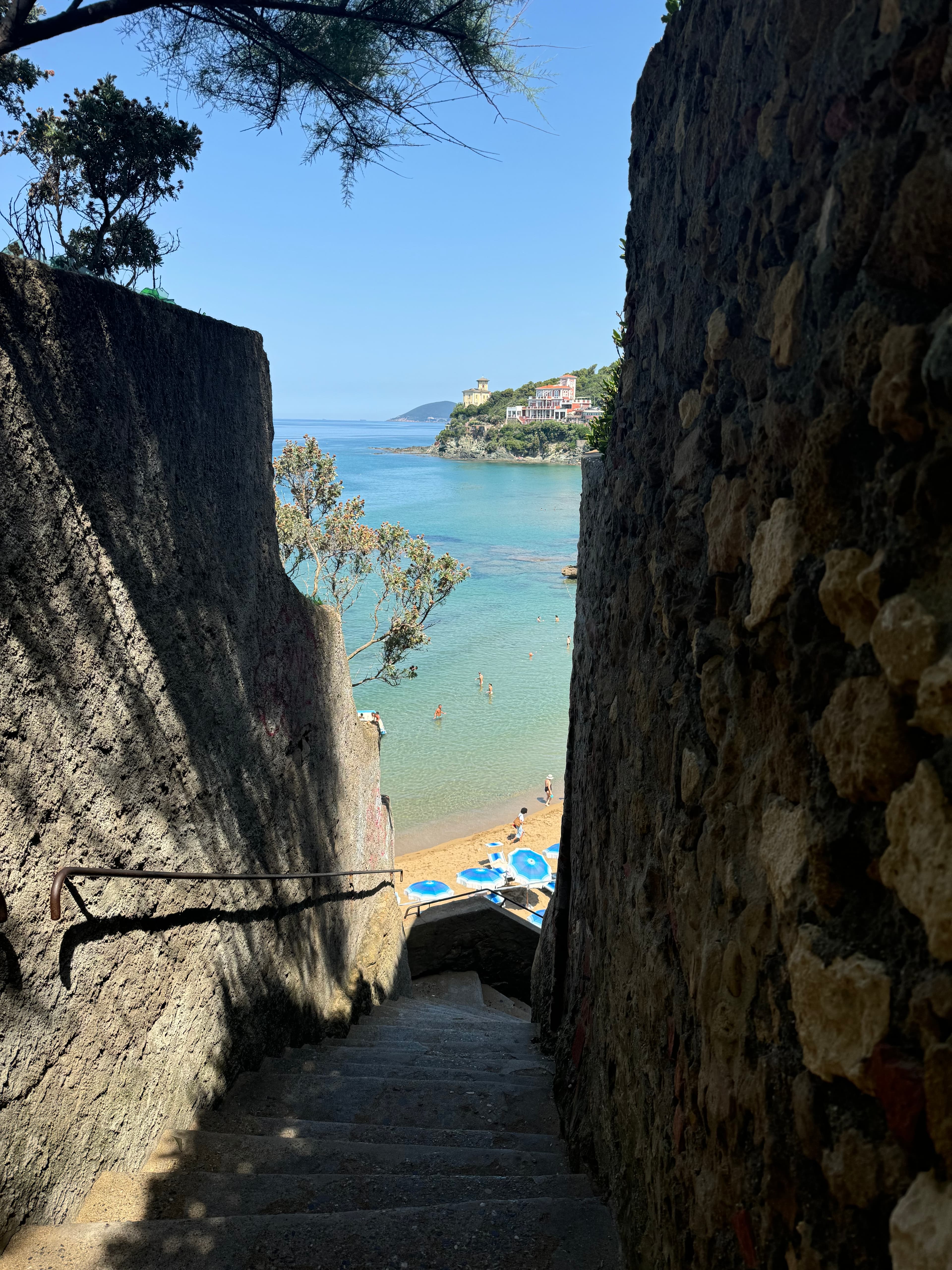 View of a steep staircase leading down towards a beach on a sunny day