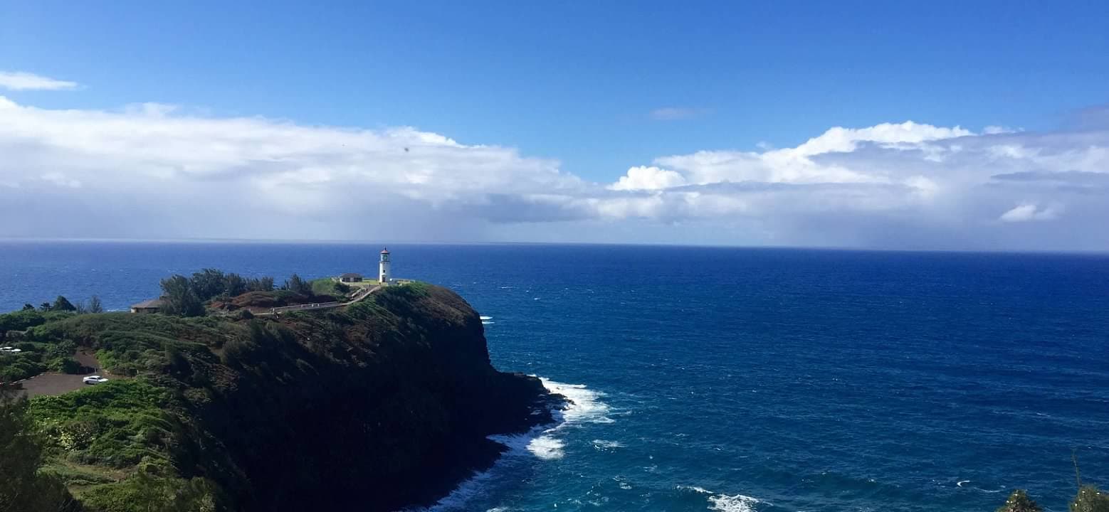 Beautiful panoramic view of the sea with a green cliffside with a lighthouse visible in the distance