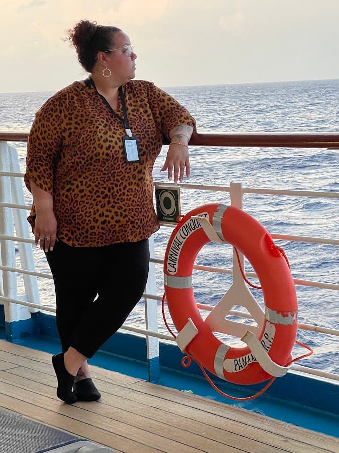 Advisor leaning against the railing of a cruise ship looking out over the sea at sunset