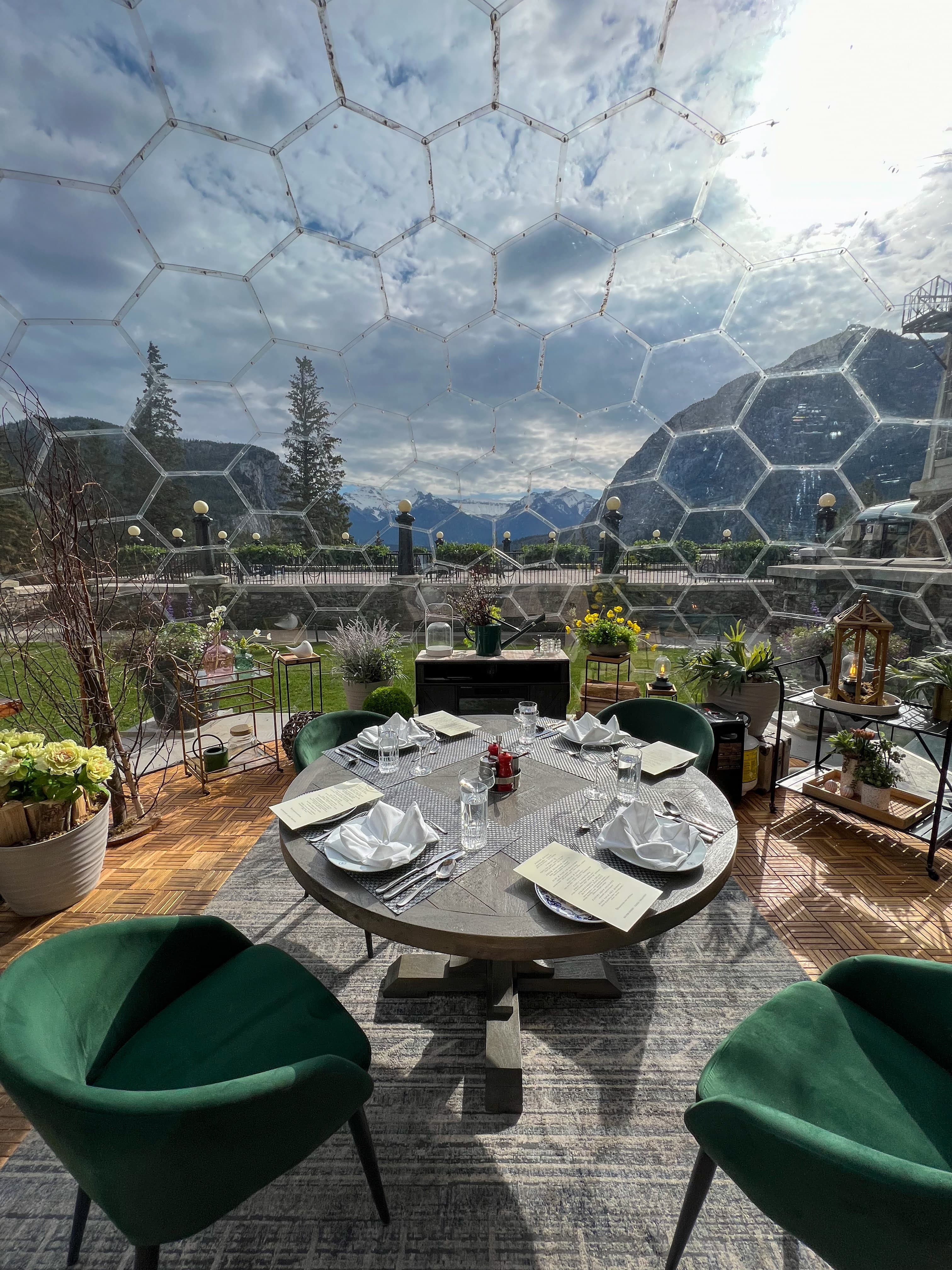 Outdoor table set with plates and glasses on a balcony overlooking a mountainous environment on a sunny day