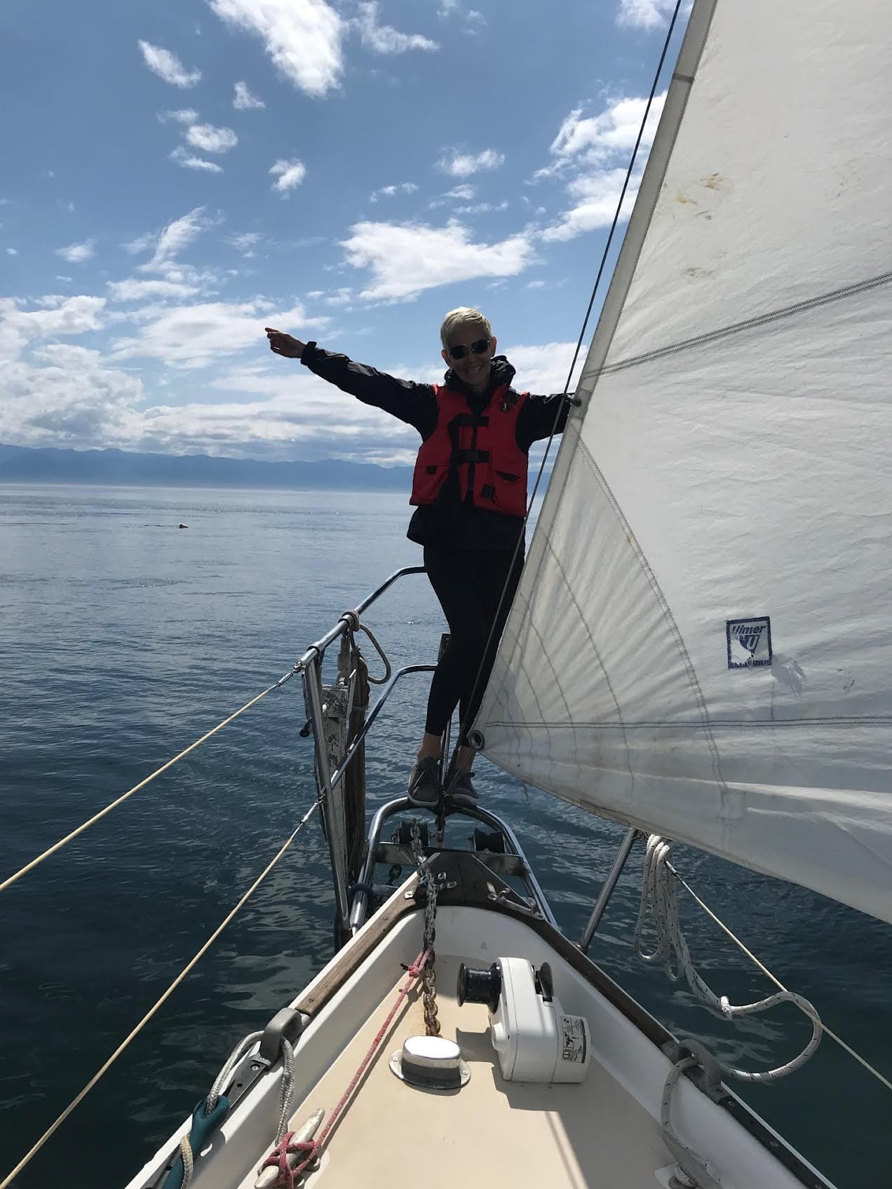 Advisor standing on the front of a sailboat on a sunny day