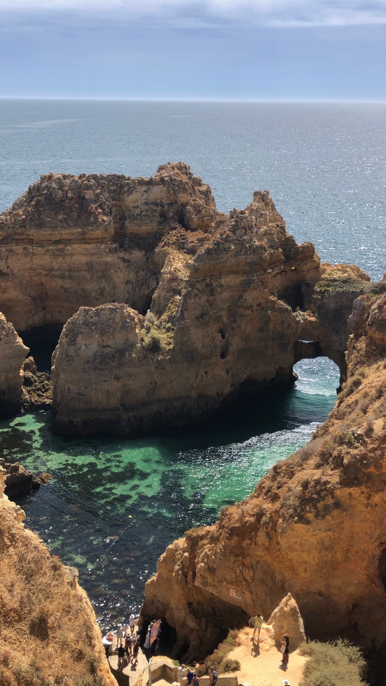 View of large rock formations at sea with an arched opening visible to one side