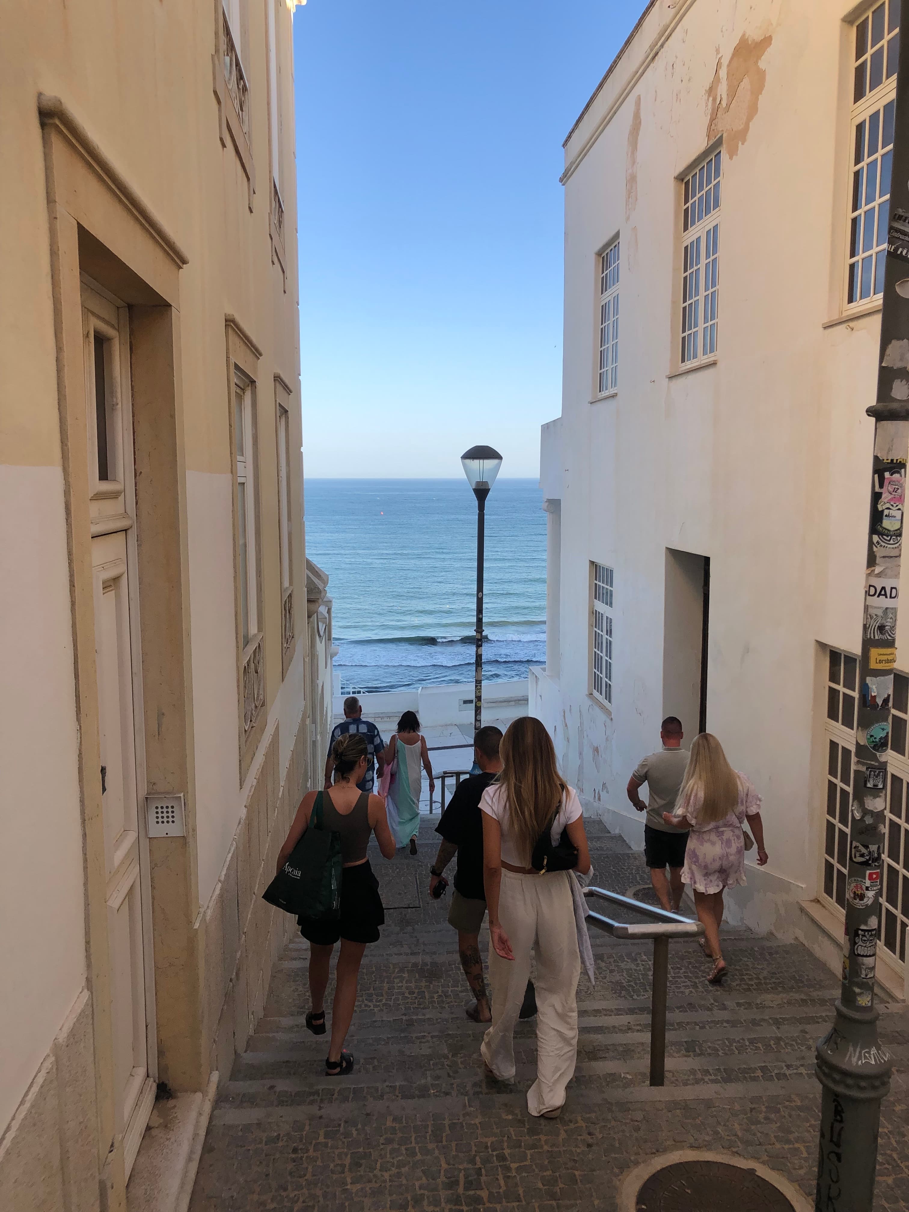 View of people walking down steps towards the sea at sundown