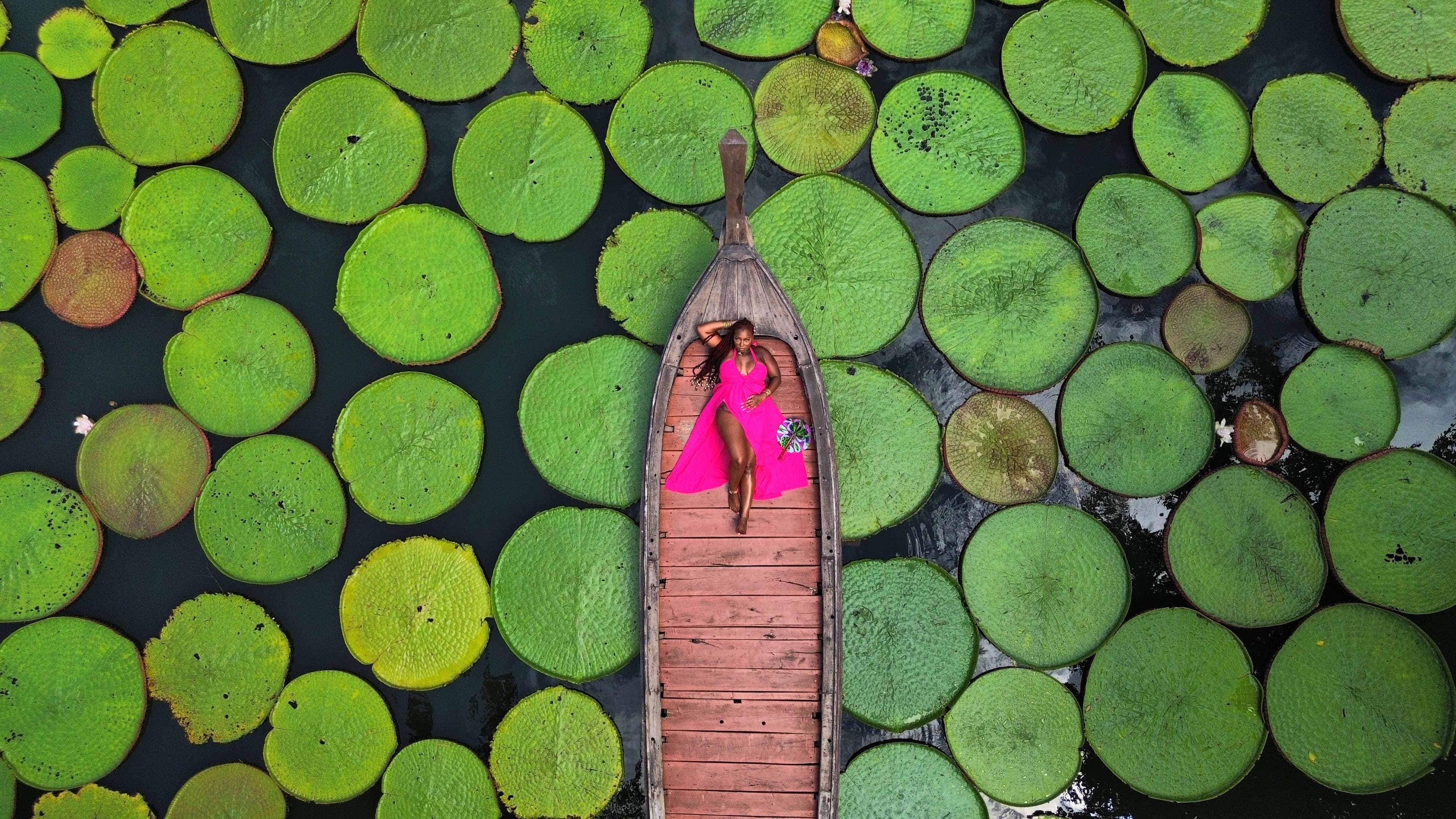 Avia posing on a boat in the water surrounded by lily pads.