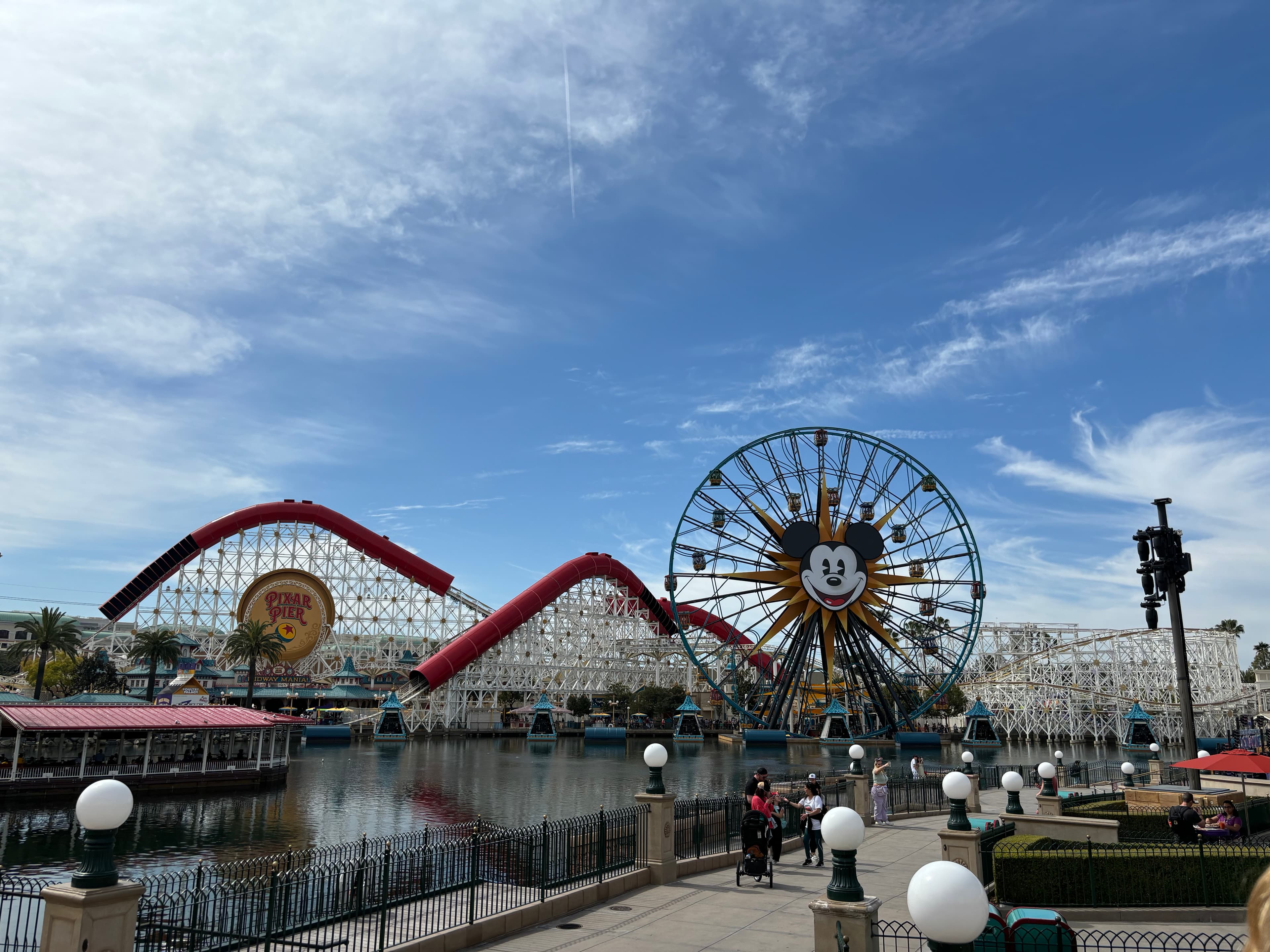 A view of a carnival during the daytime with rides and a freewheel in the distance. 