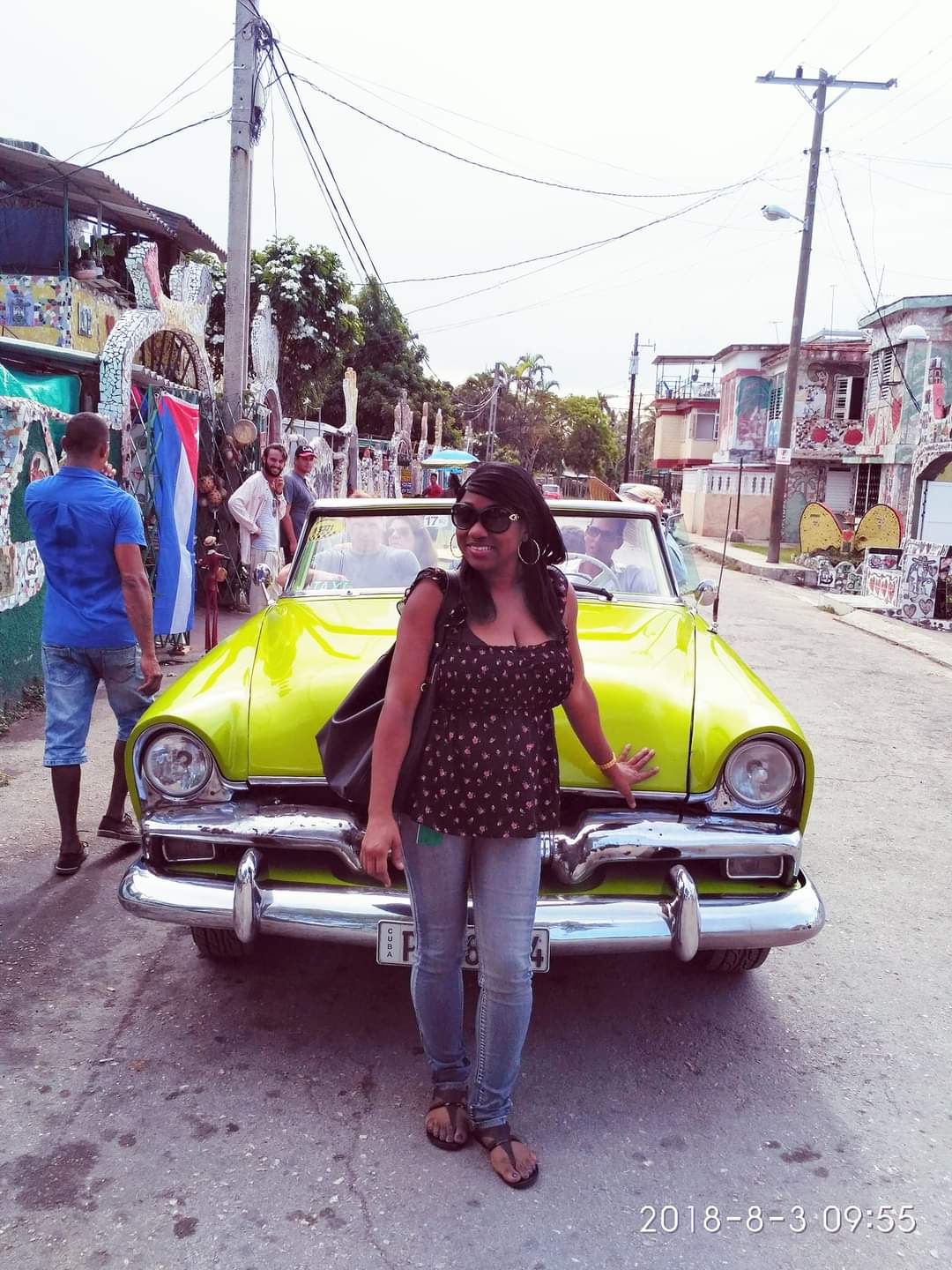 Advisor posing in front of a yellow classic car on a street in Cuba