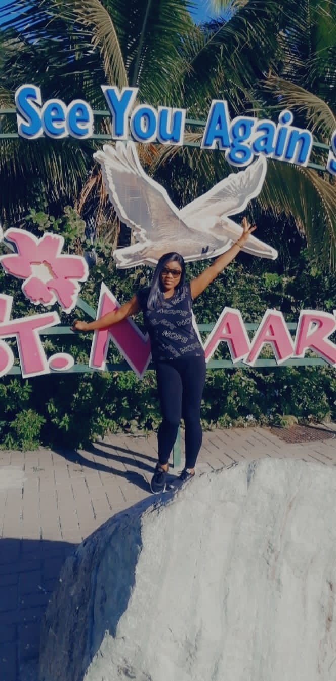 Advisor posing with arms outstretched in front of a sign with a seagull in St. Maarten