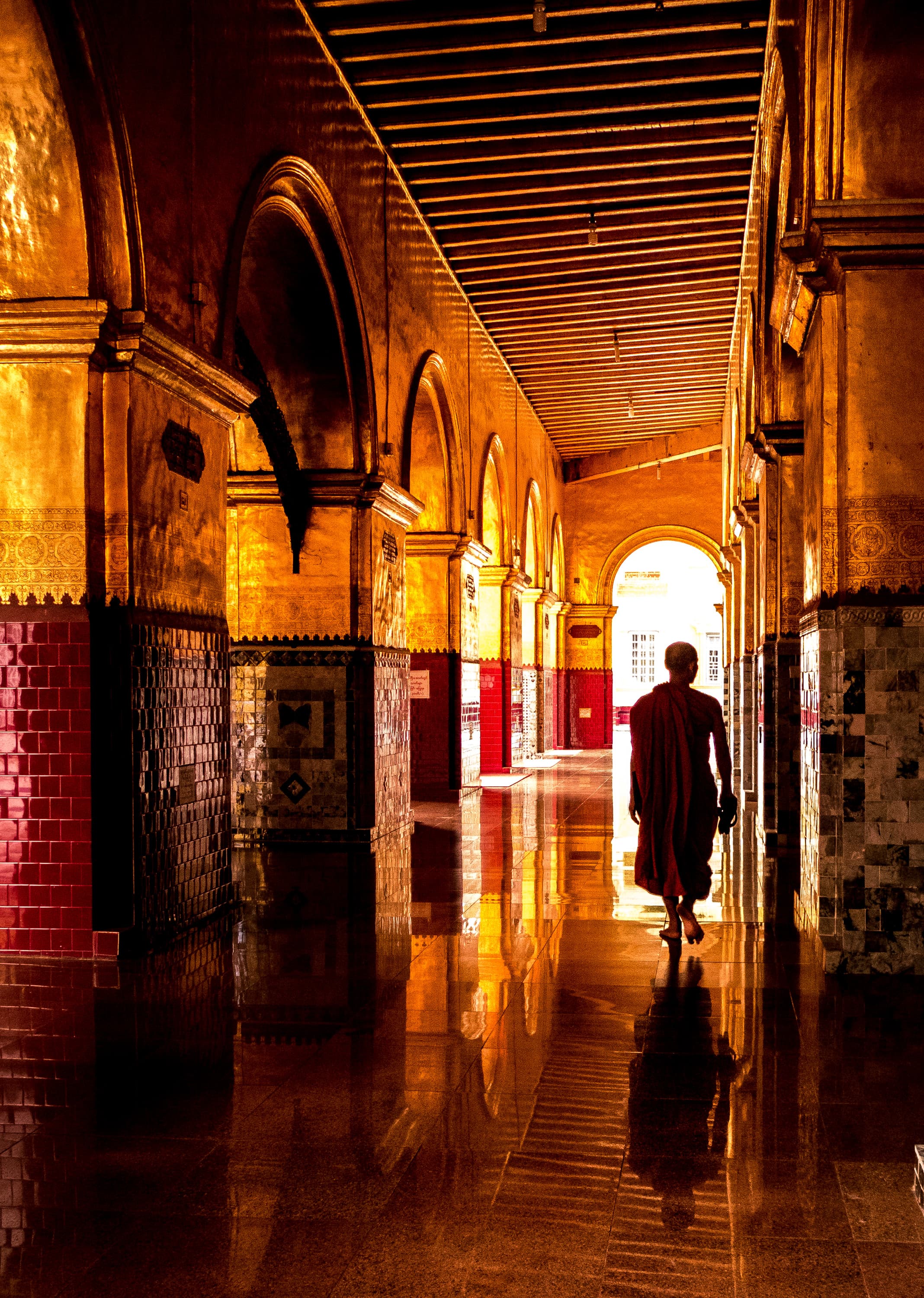 A view of the inside of a temple with a monk in the distance.