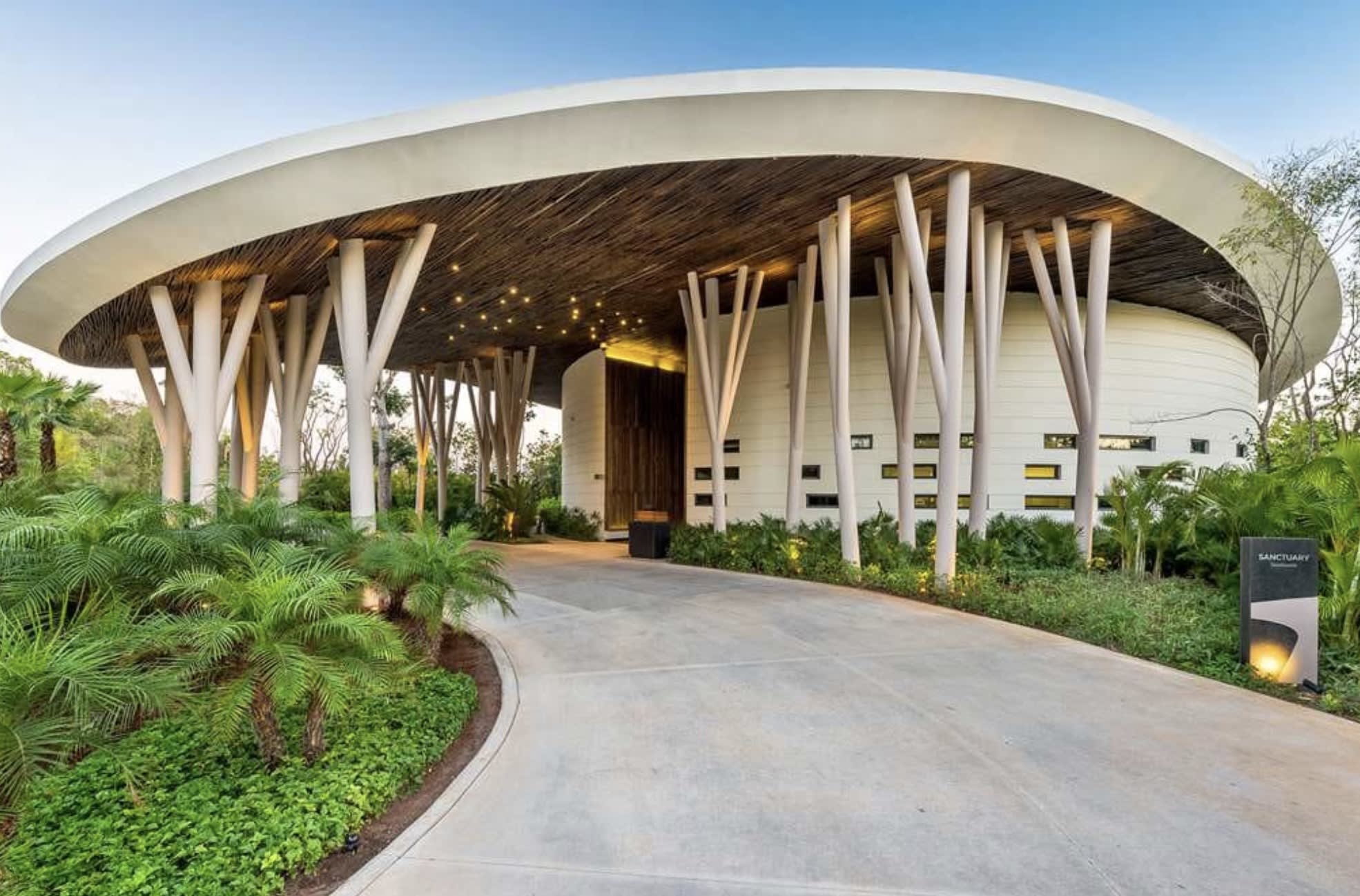 curved entryway to a hotel with skinny tree-like columns and a driveway to the front door