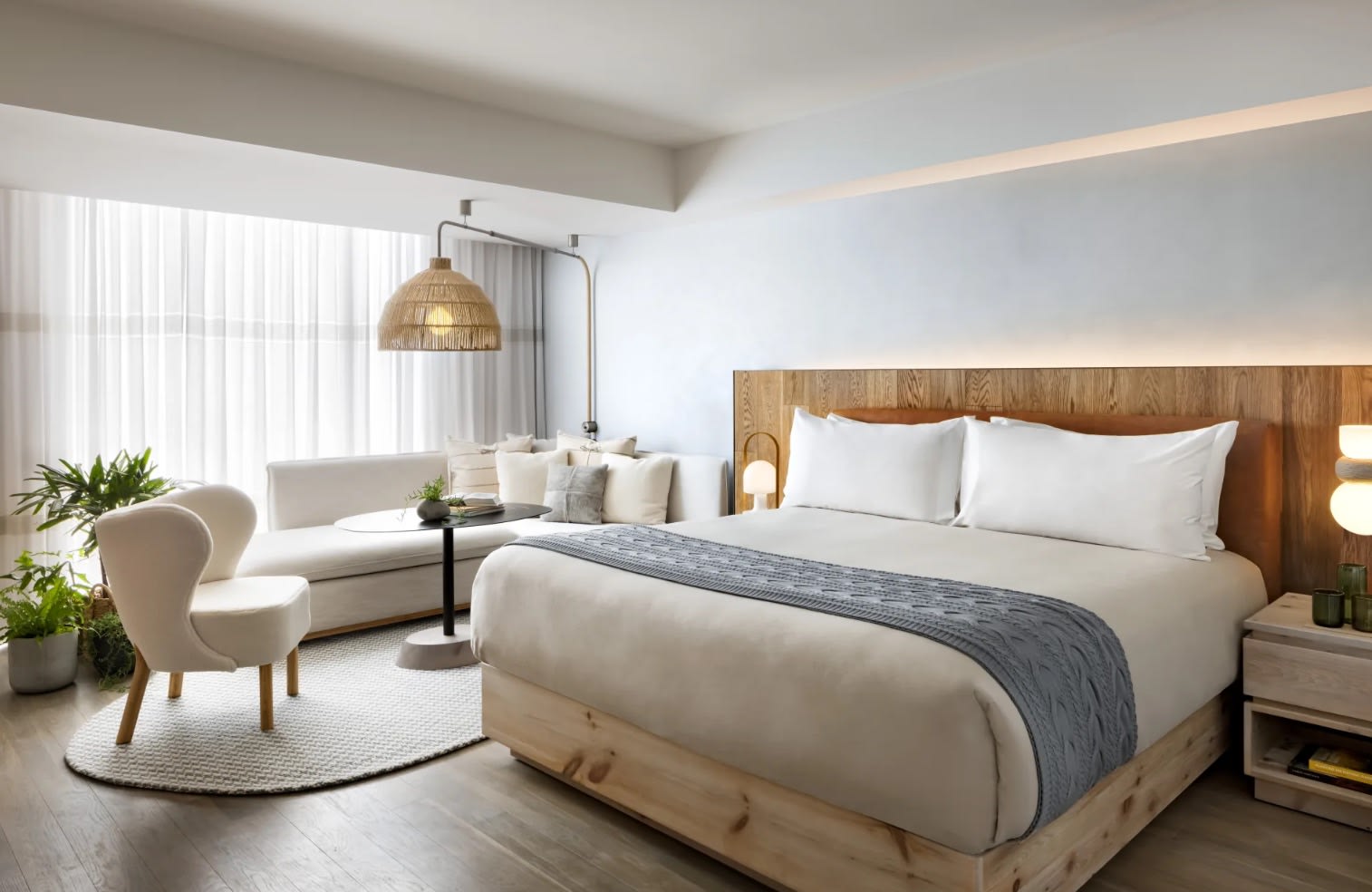 white bedroom with natural wood bed and seating area