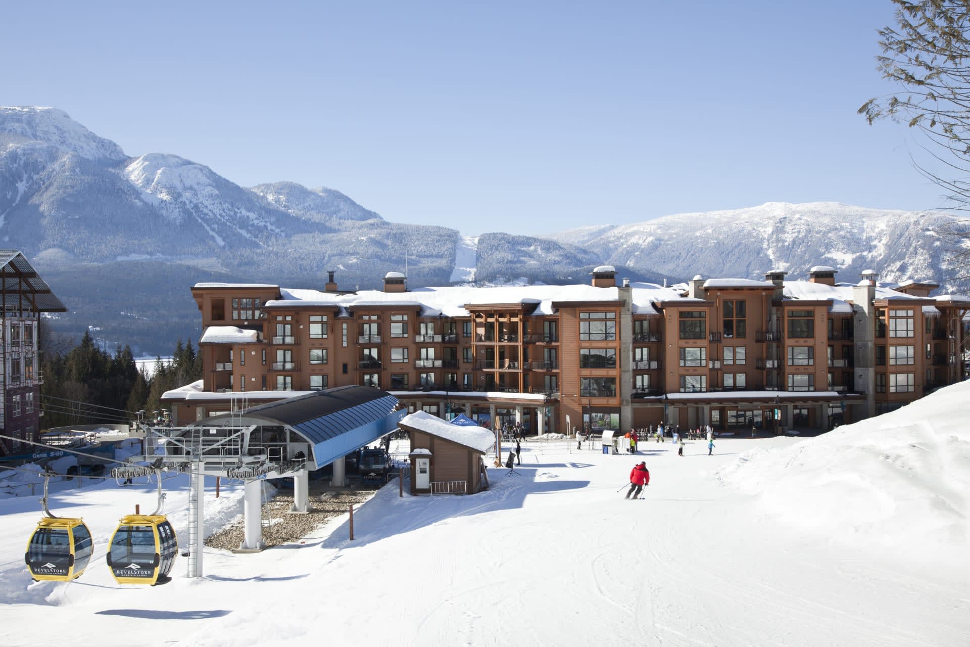 skiers in front of a hotel with a ski lift attached to the left