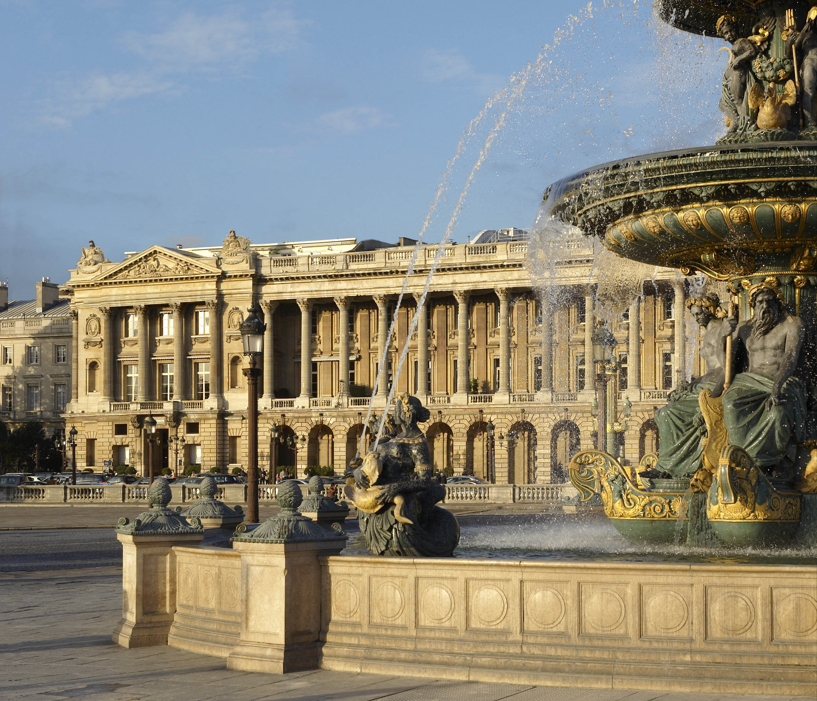 A view of a fountain in a square in front of a grand hotel building in Paris
