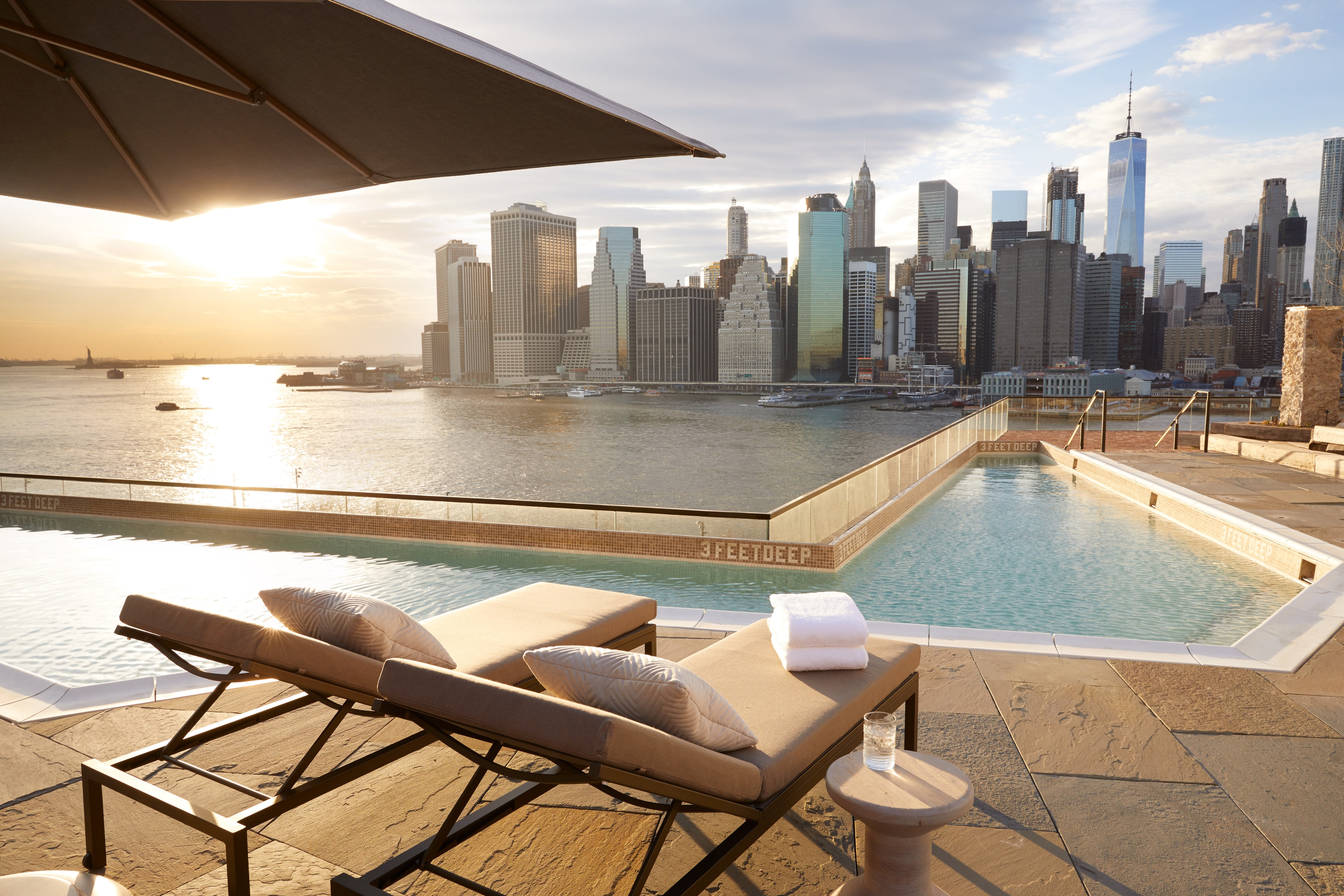 A rooftop pool area with loungers overlooking the New York city skyline