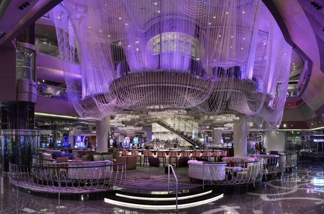 A glamorous hotel bar area with hanging chandelier-style decoration and purple lighting