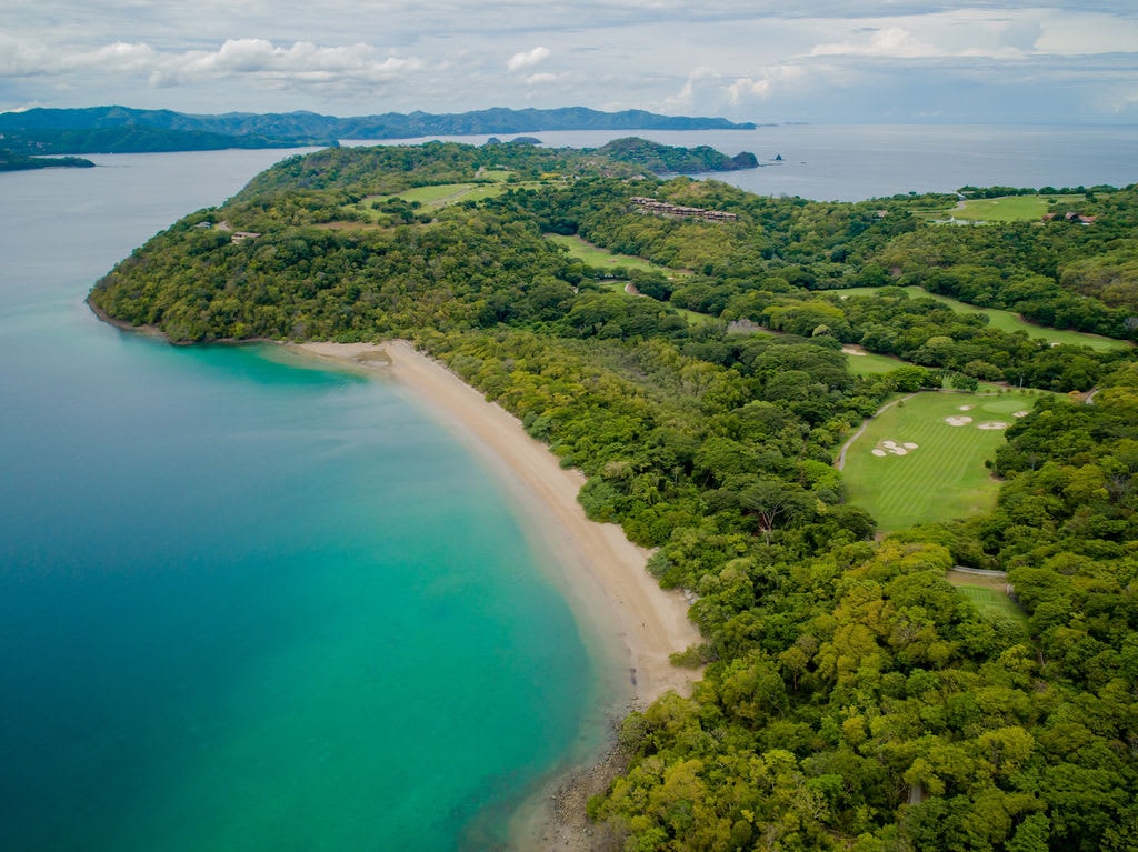 aerial view of a seaside golf course near a jungly peninsula