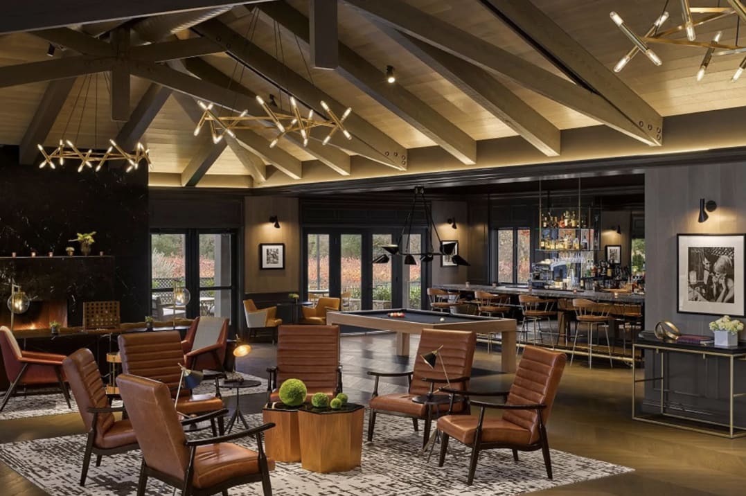 A lounge area and bar under vaulted ceiling with brown leather seating and dark interiors