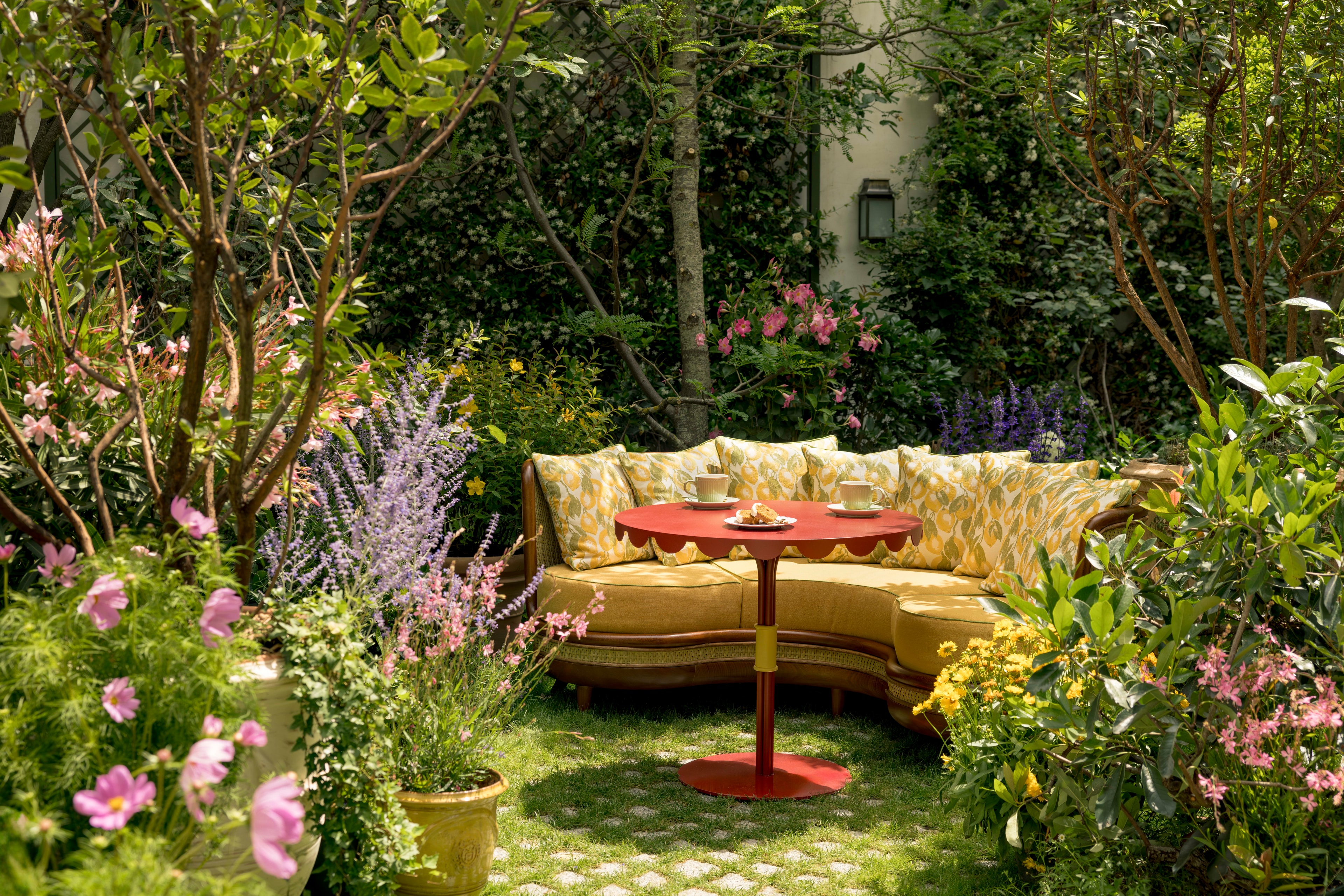 A colorful hotel garden with a yellow sofa and orange round table.