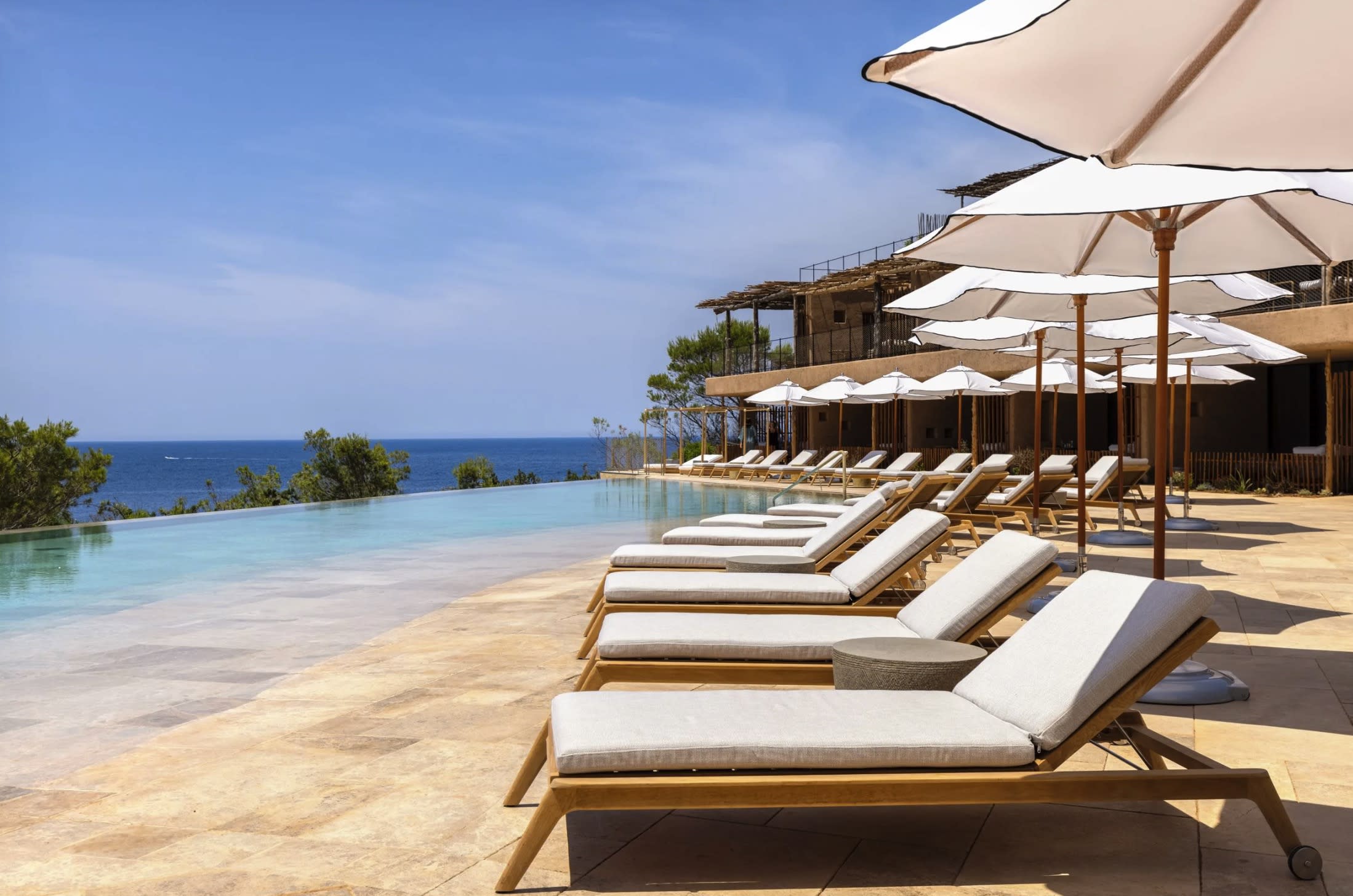 sun loungers with white umbrellas by a pool with an ocean view