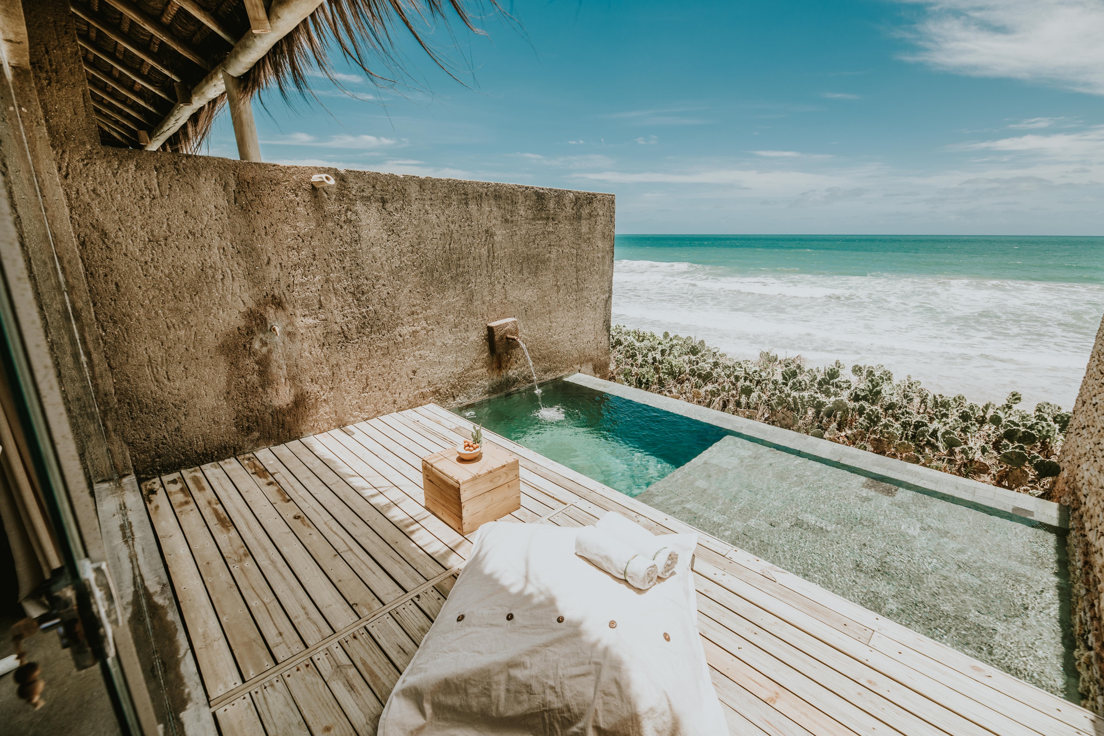 A hotel terrace overlooking the ocean with a plunge pool and wooden deck