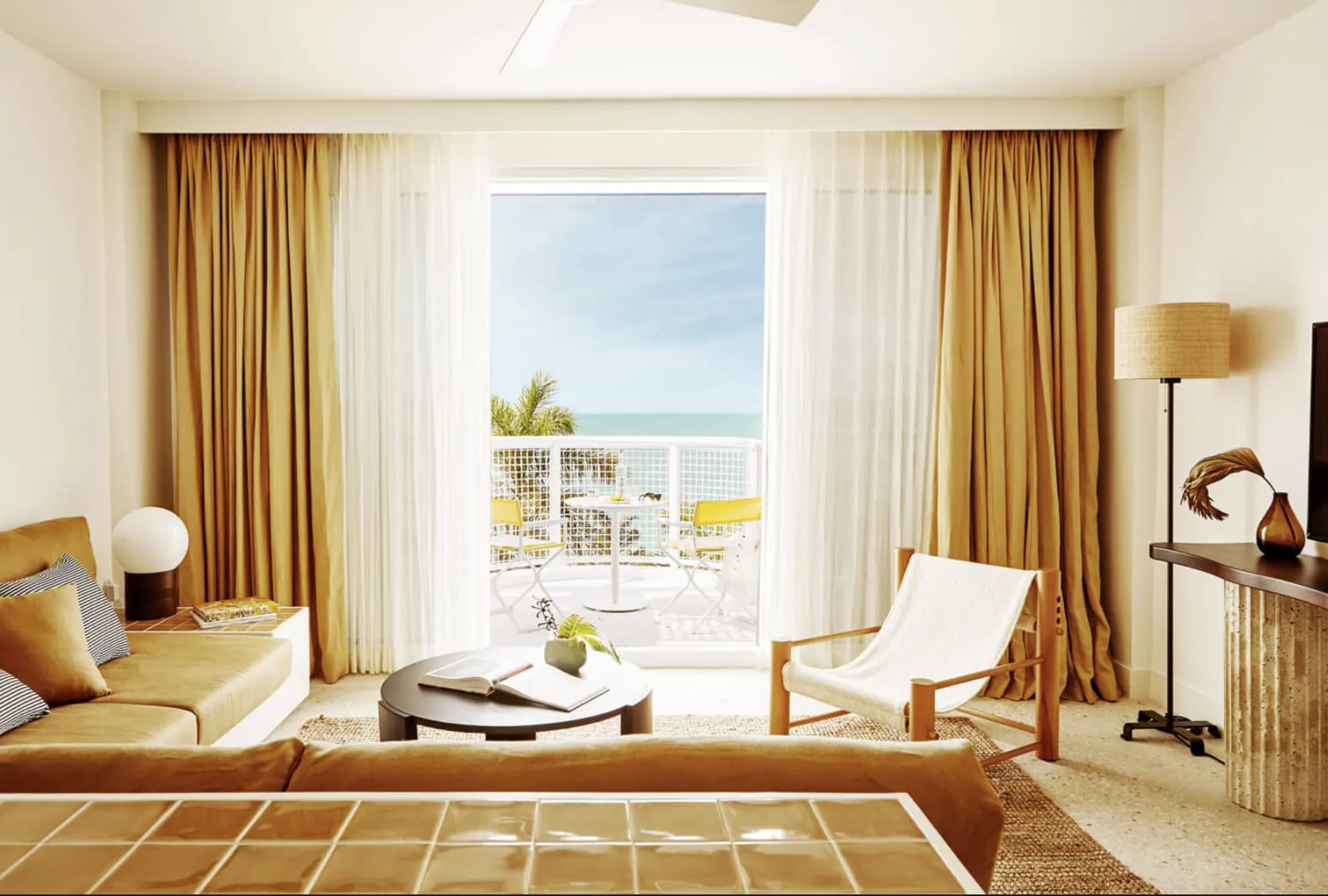 A coastal hotel room with eclectic furniture and a balcony with ocean views