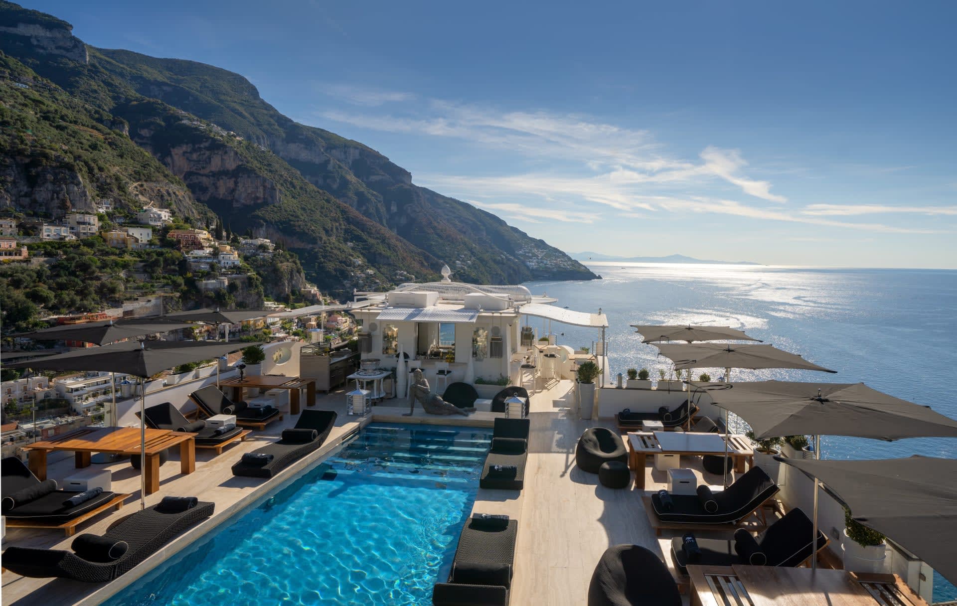 Aerial view of rooftop pool with hills on the edge of the ocean in the background during day