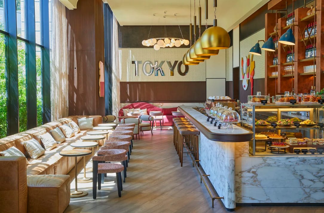 A bright, contemporary cafe area with a hanging lights over a the bar and a gold Tokyo sign on the wall