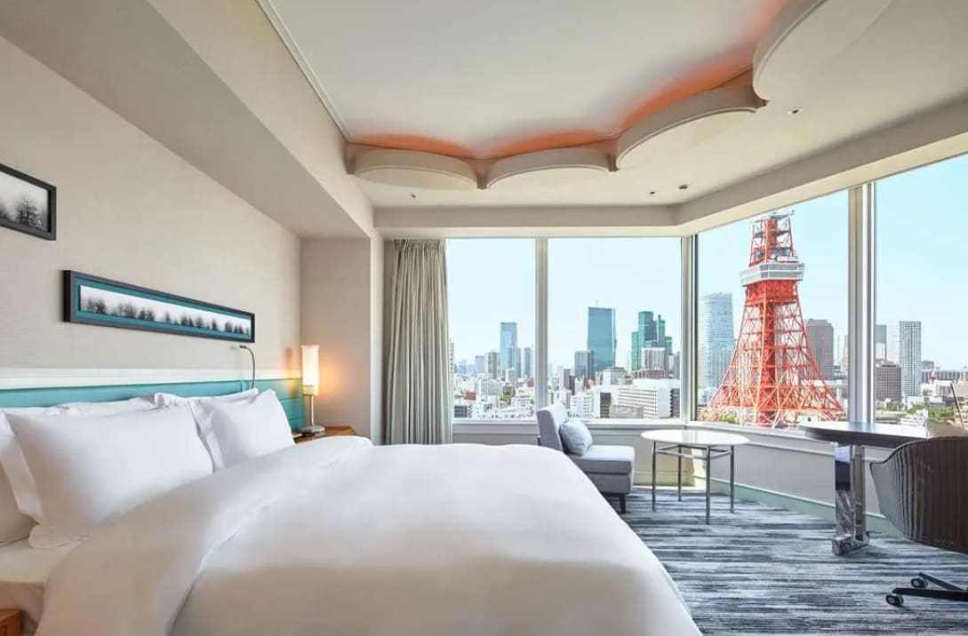 A bright hotel room with large windows showing the red Tokyo Tower and city skyscrapers