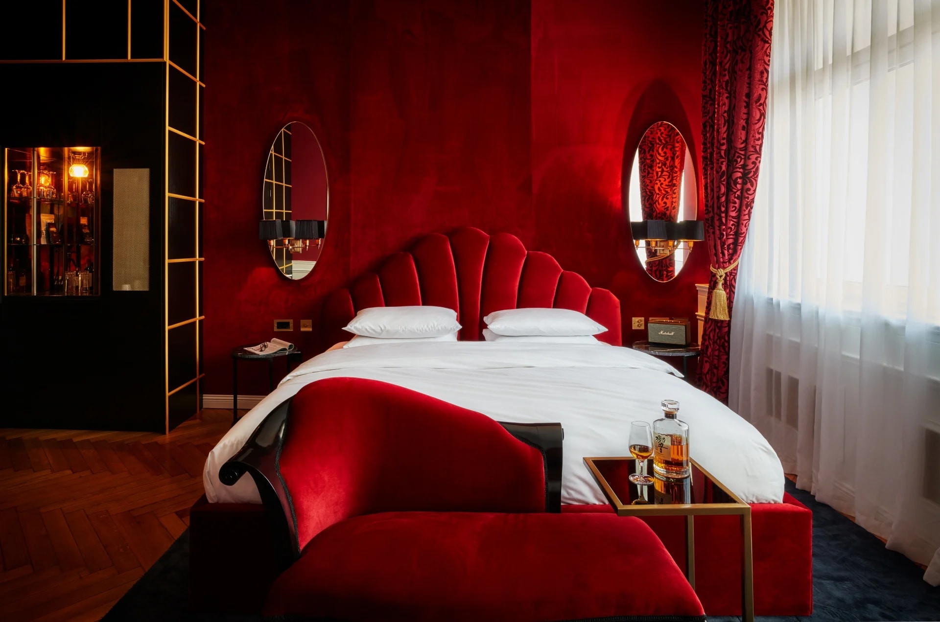 A red velvet covered hotel room with white bed sheets