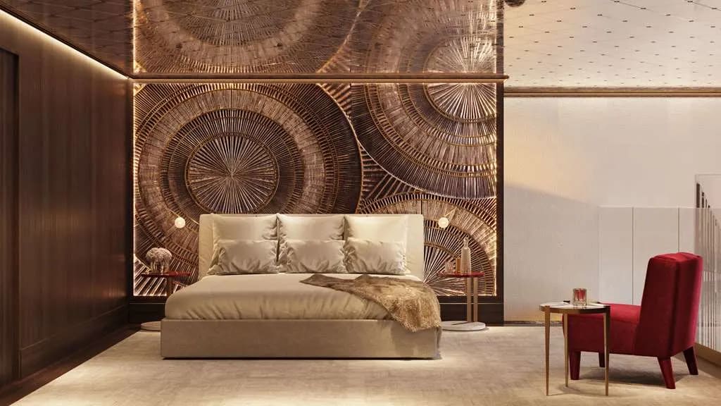 A modern hotel room with dark brown patterned wall behind a tan bed and right side chair off to the side