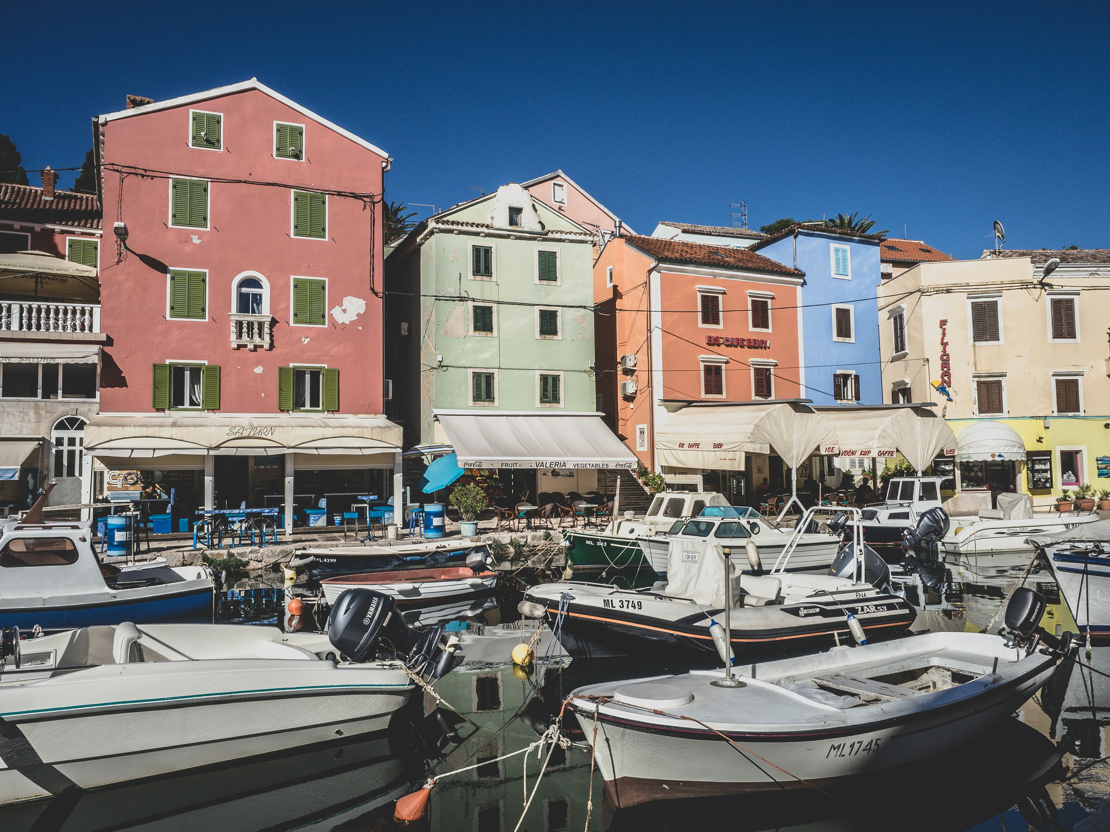 A picturesque harbor with colorful, typical buildings and boats docked, with restaurants lining the sidewalk