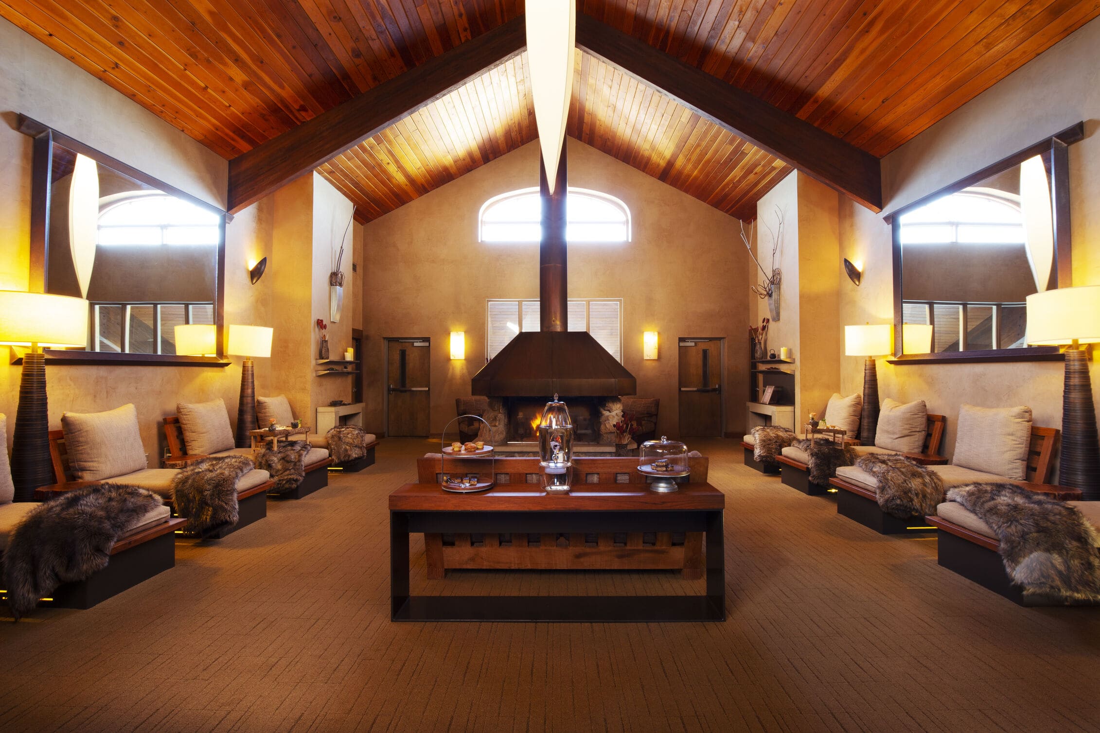 A dimly lit lounge with vaulted ceilings and a large fireplace and seating