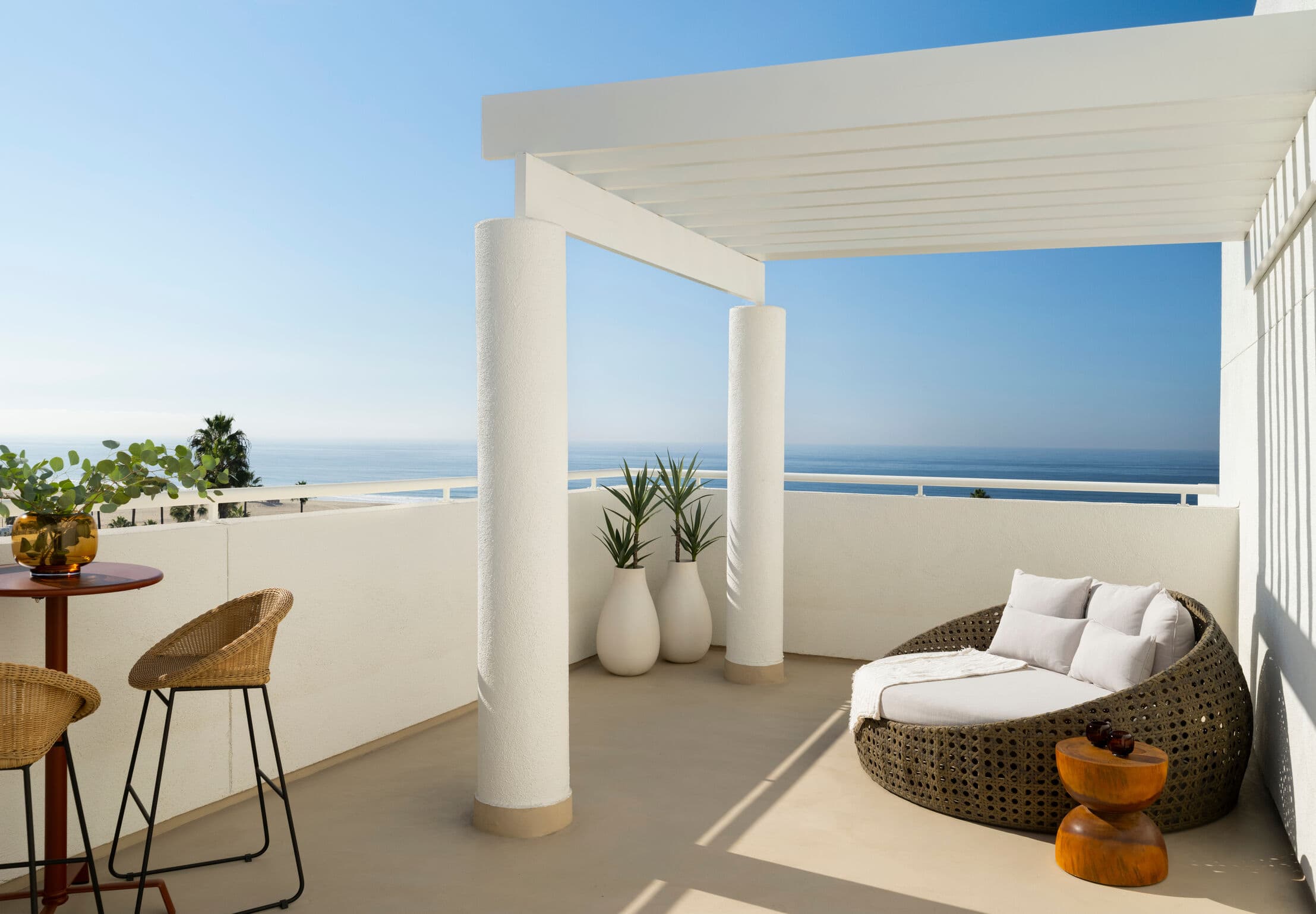 A white balcony with double loveseat and white gazebo with sea views